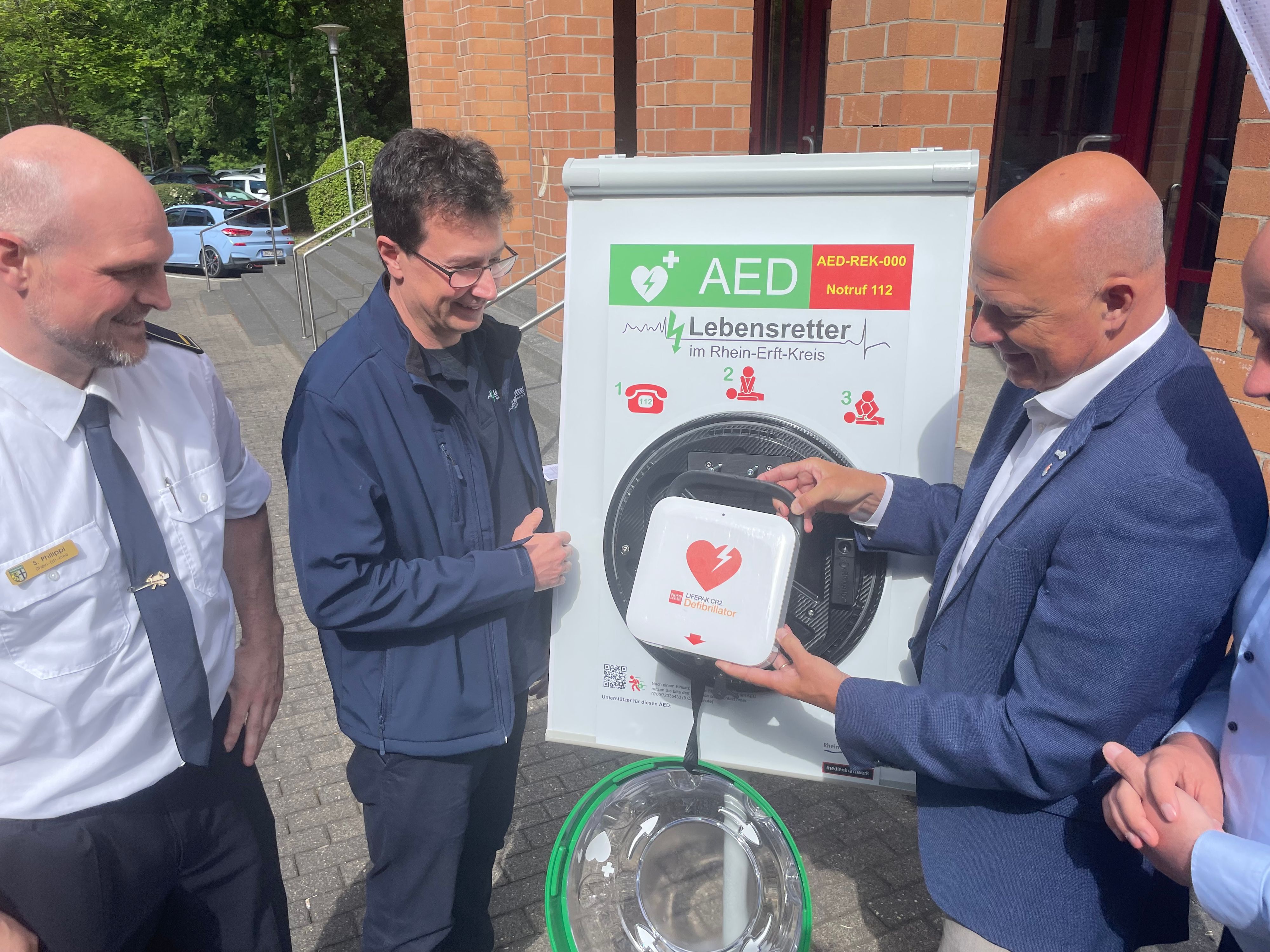 Das Foto zeigt die Vertreter des Kreises und des Vereins mit einem Defibrillator.