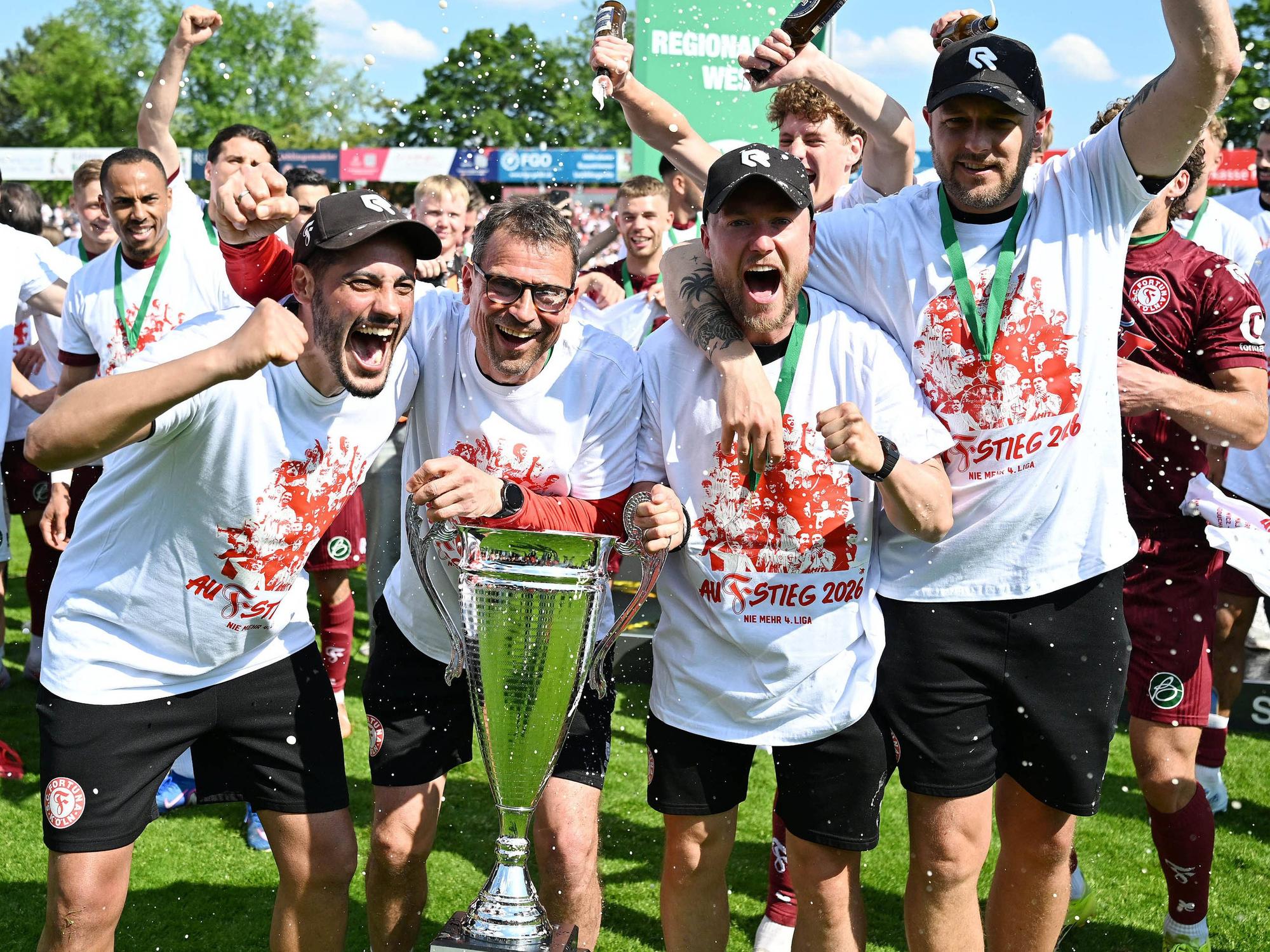 09.05.2026, xophax, Fussball Regionalliga West. SC Fortuna Köln gegen Sportfreunde Siegen. Meister der Regionalliga West . Fortuna Köln ist aufgestiegen . Feier im Südstadion nach dem Schlusspfiff. Siegerehrung mit Meisterpokal. Trainerteam v.l.n.rechts : Hamdi Dahmani , Matthias Mink , Martin Grund, Sven Bacher alle Fortuna Köln Koeln *** 09 05 2026, xophax, Soccer Regionalliga West SC Fortuna Köln vs Sportfreunde Siegen Champion of the Regionalliga West Fortuna Köln has been promoted Celebration in the Südstadion after the final whistle Award ceremony with championship trophy Coaching team from left to right Hamdi Dahmani , Matthias Mink , Martin Grund, Sven Bacher all Fortuna Köln Koeln