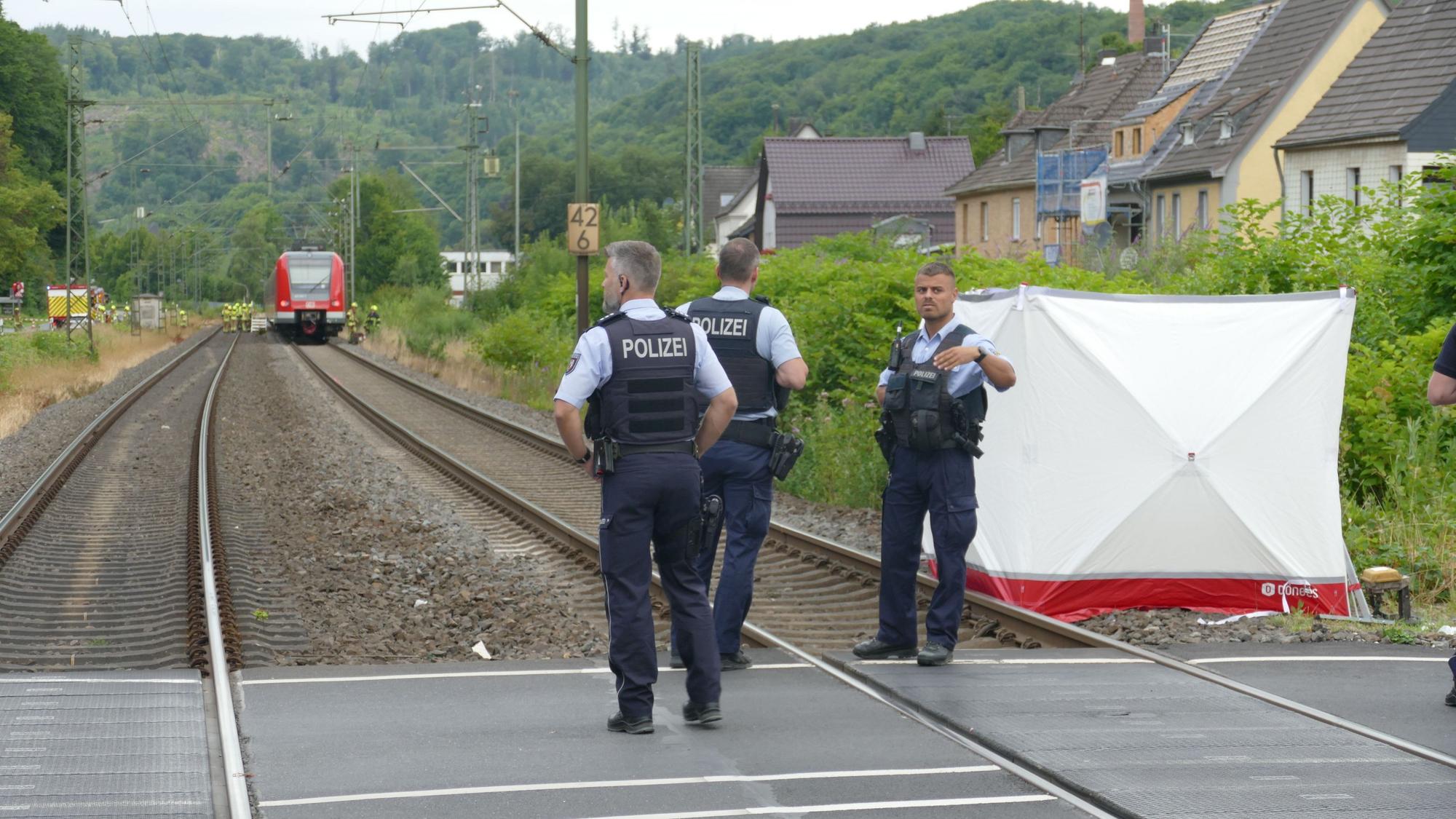 Polizisten stehen nach einem Unfall mit einem Zug an einem Bahnübergang.