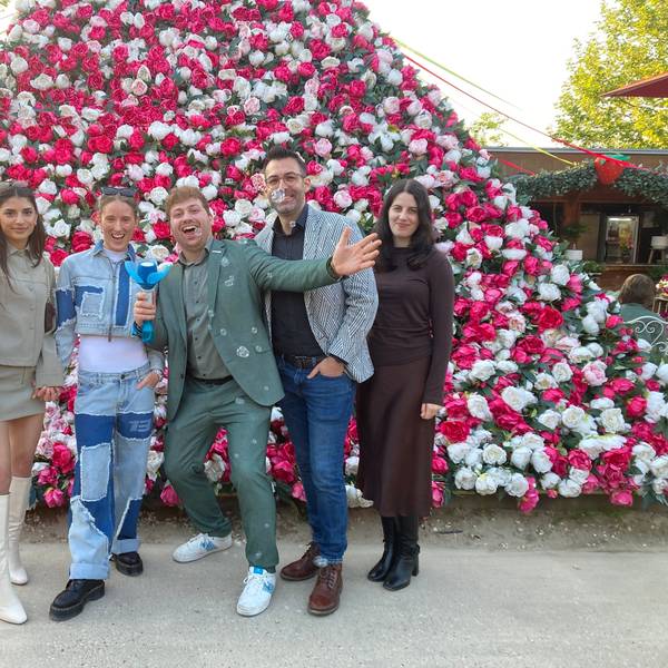 Auf dem Bild ist eine Gruppe von jungen Leuten zu sehen, die vor einer Pyramide aus Blumen stehen.