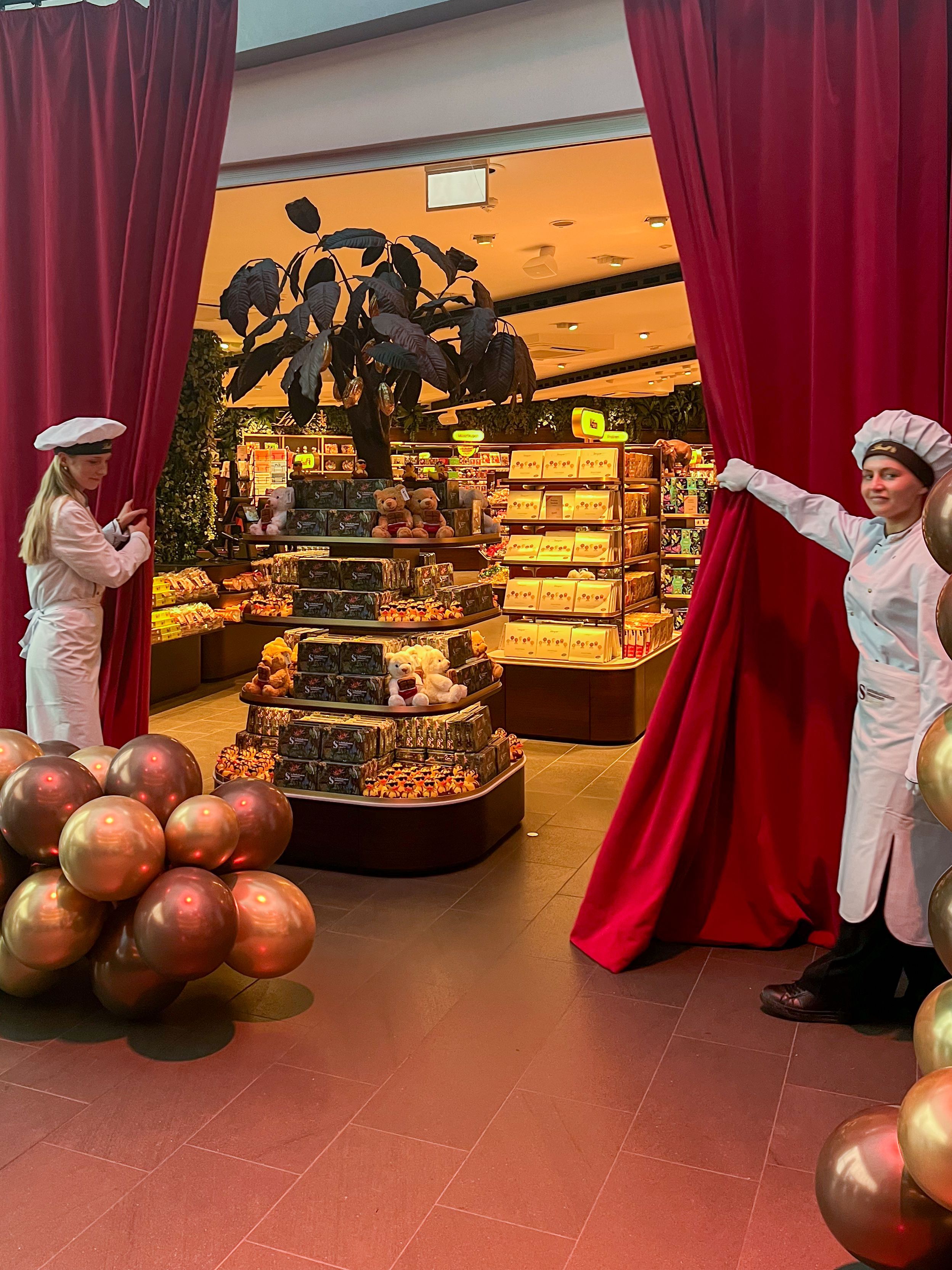 Zwei Angestellte des Schokoladenmuseums ziehen den Vorhang vor dem neuen Museumsshop zur Seite.