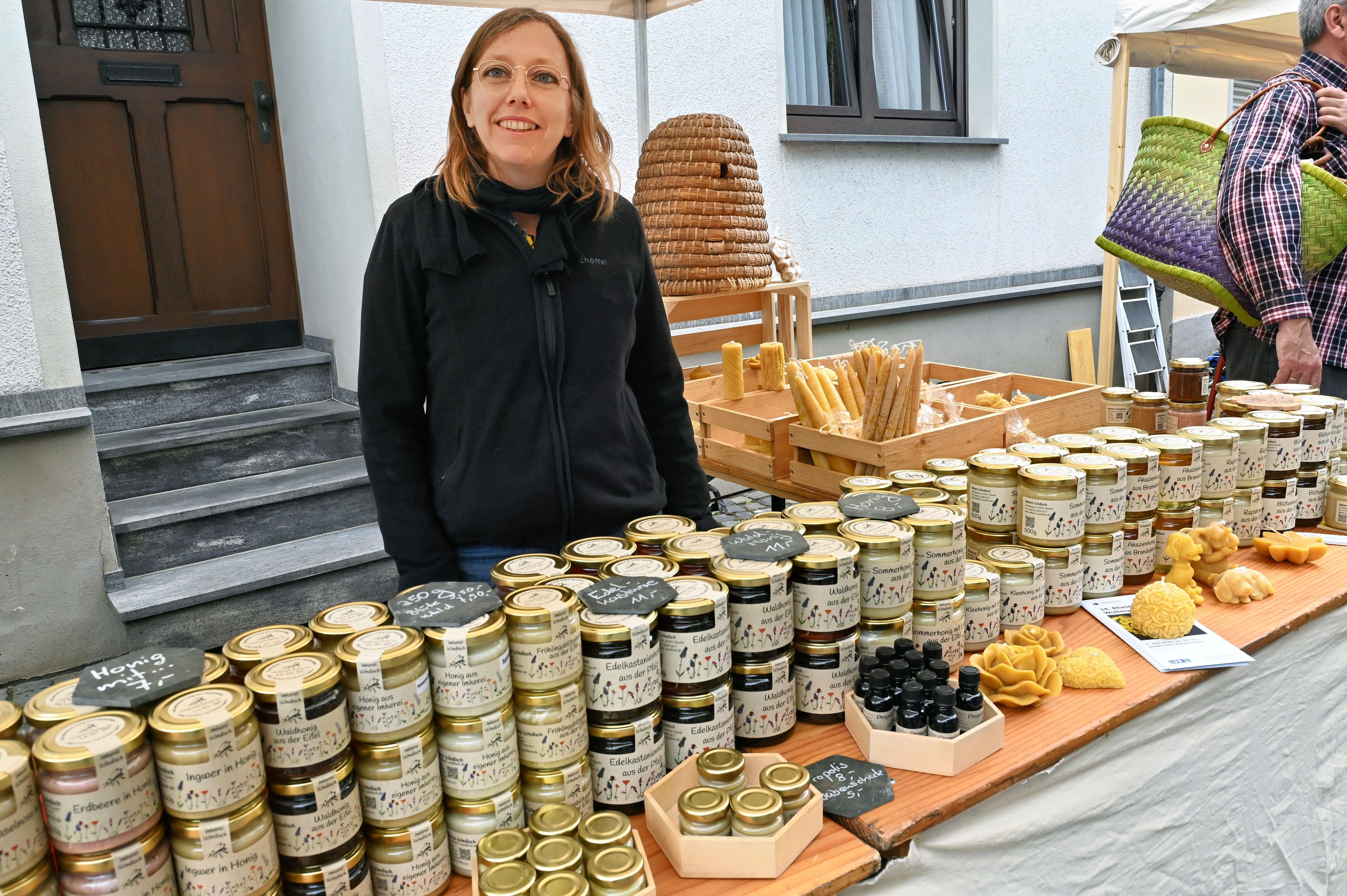 Eine Frau steht hinter einer Reihe gestapelter Honiggläser.