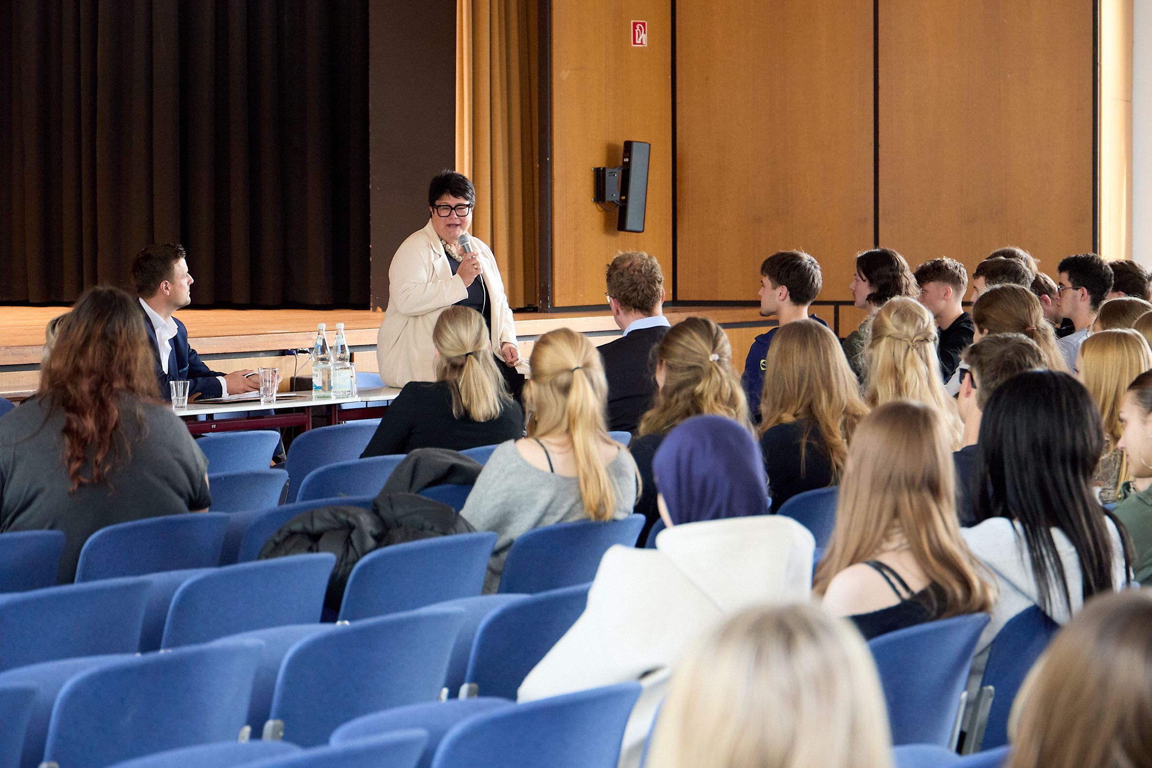 Sabine Verheyen spricht vor den zuhörenden Schülern in der Aula in ein Mikrofon.