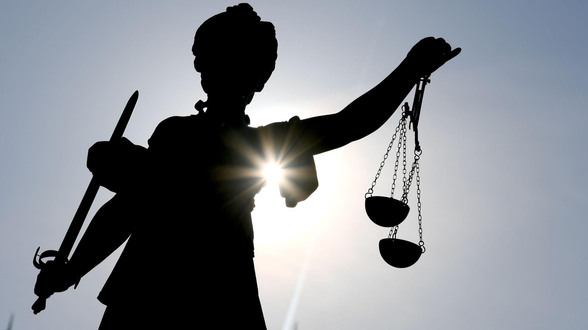 Die Göttin Justitia im Gegenlicht auf dem Gerechtigkeitsbrunnen in Frankfurt am Main.