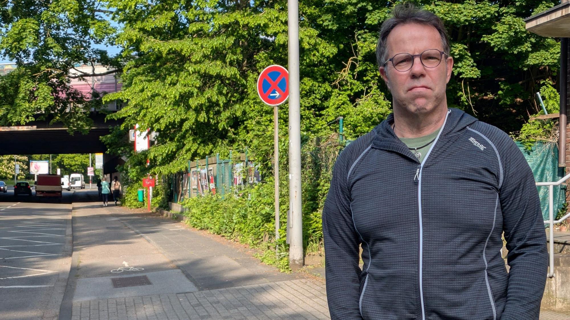 Ein Mann steht am Rand einer Straße.