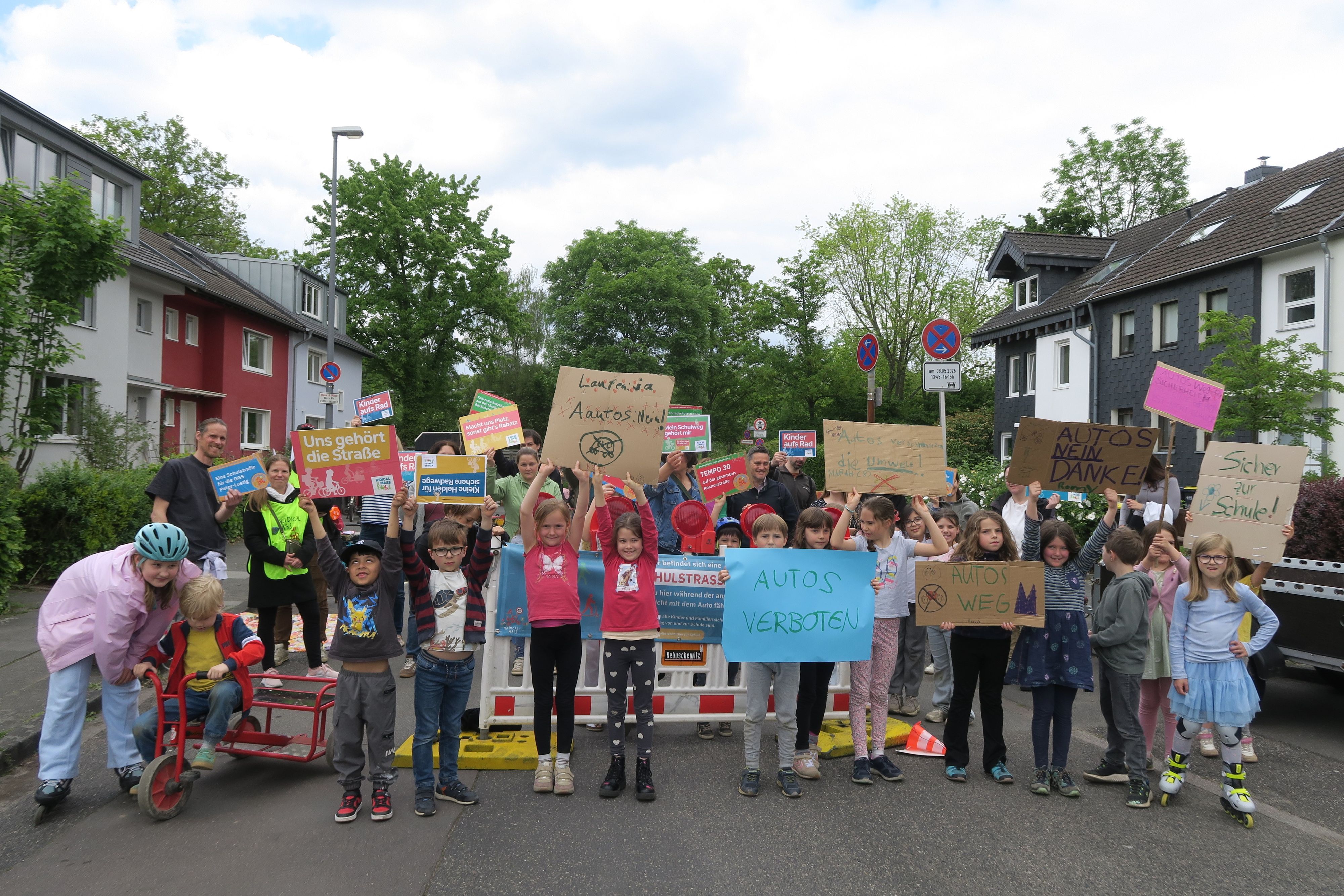 Kinder mit Plakaten und Transparenten stehen auf einer Straße.