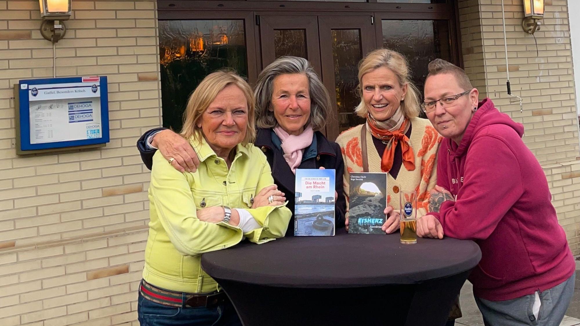 Vier Frauen stehen um einen Stehtisch herum vor einer Kneipe.