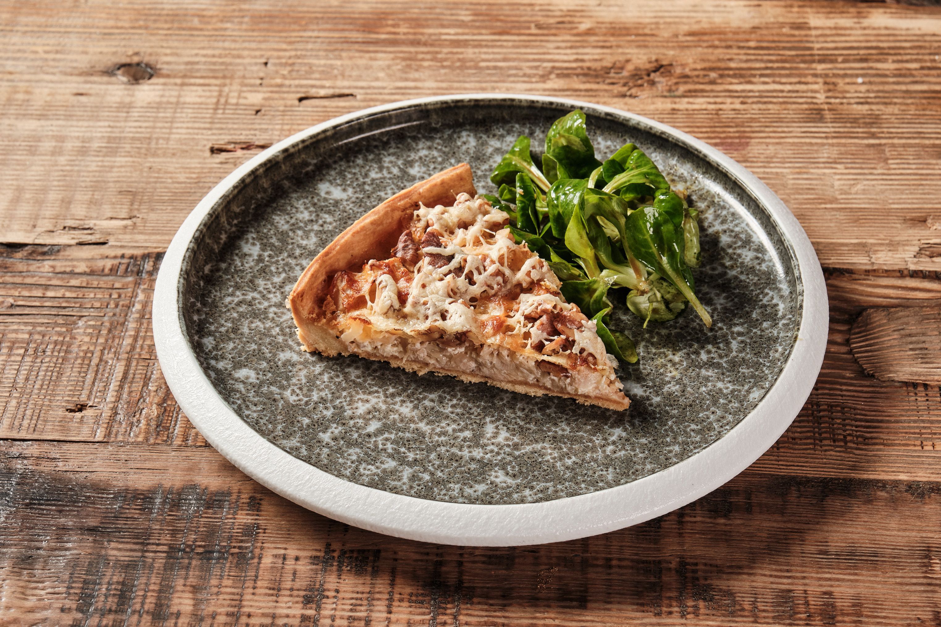 Ein Stück Quiche neben etwas Salat.