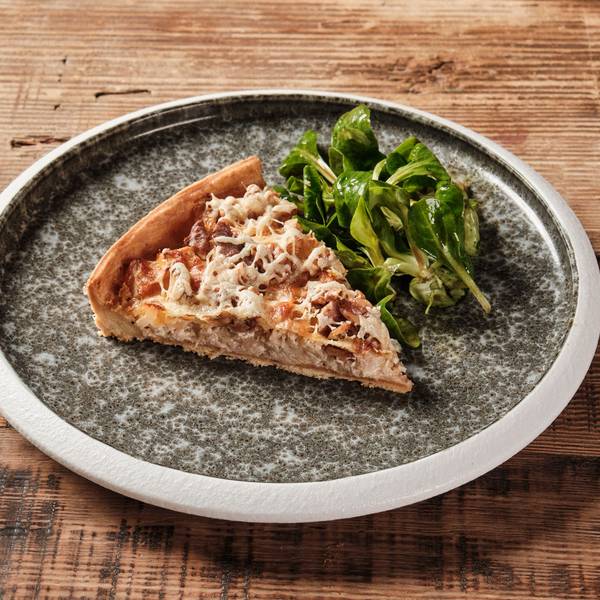 Ein Stück Quiche neben etwas Salat.