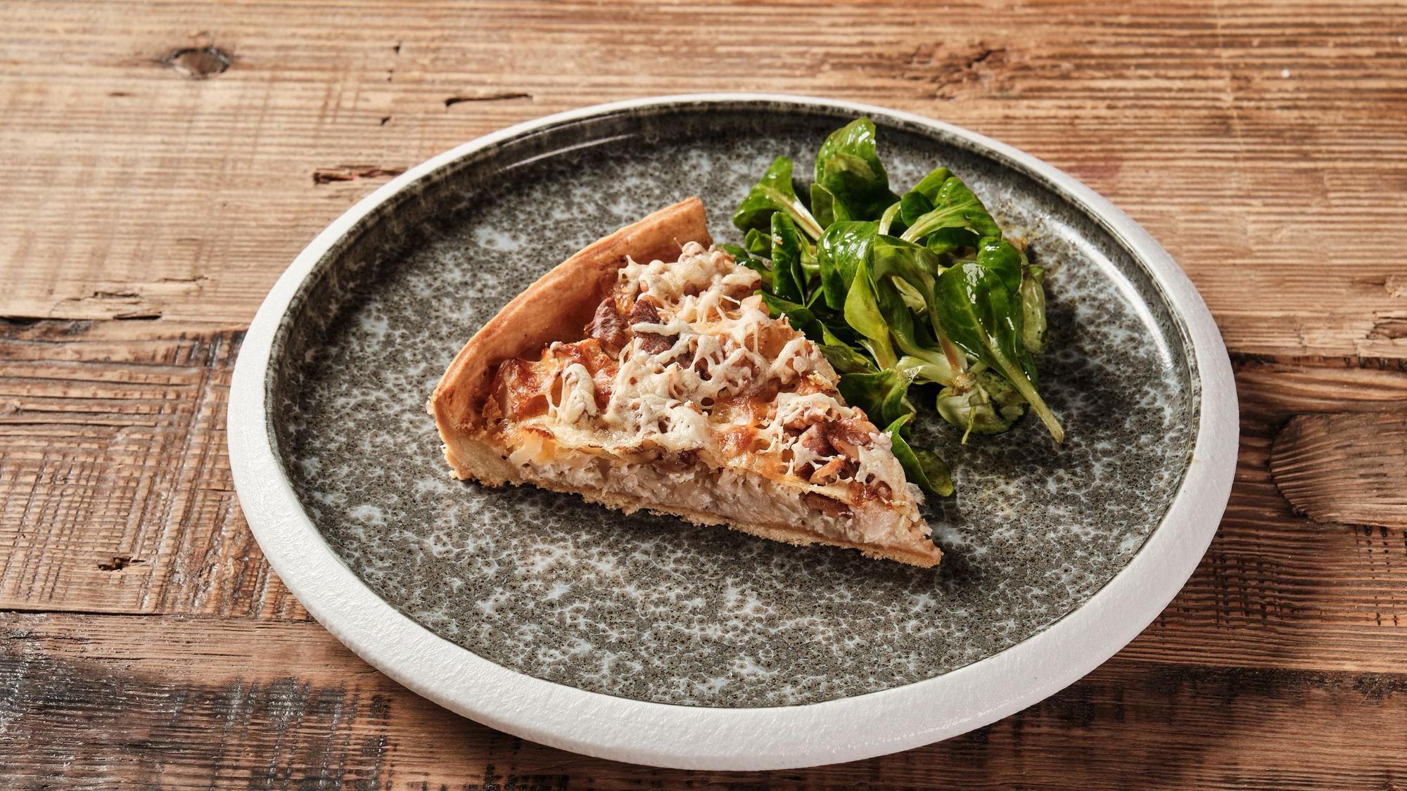 Ein Stück Quiche neben etwas Salat.