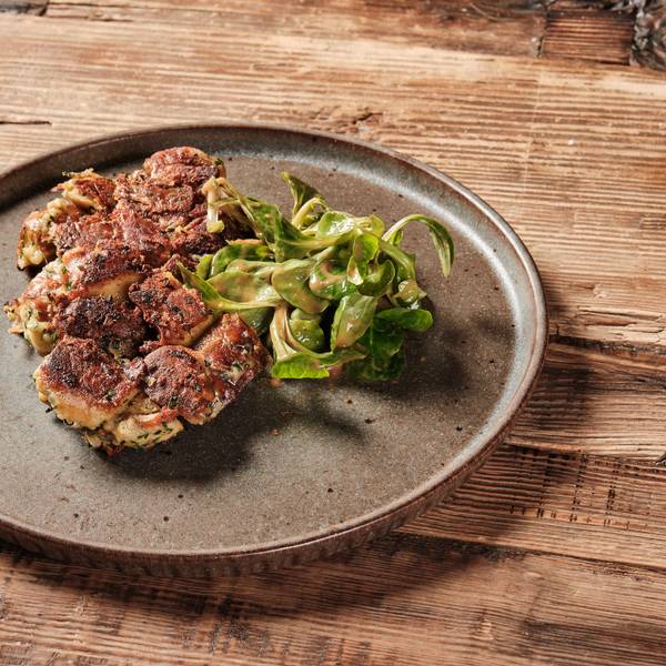 Knödel angerichtet auf einem Teller mit einem Salatblatt daneben