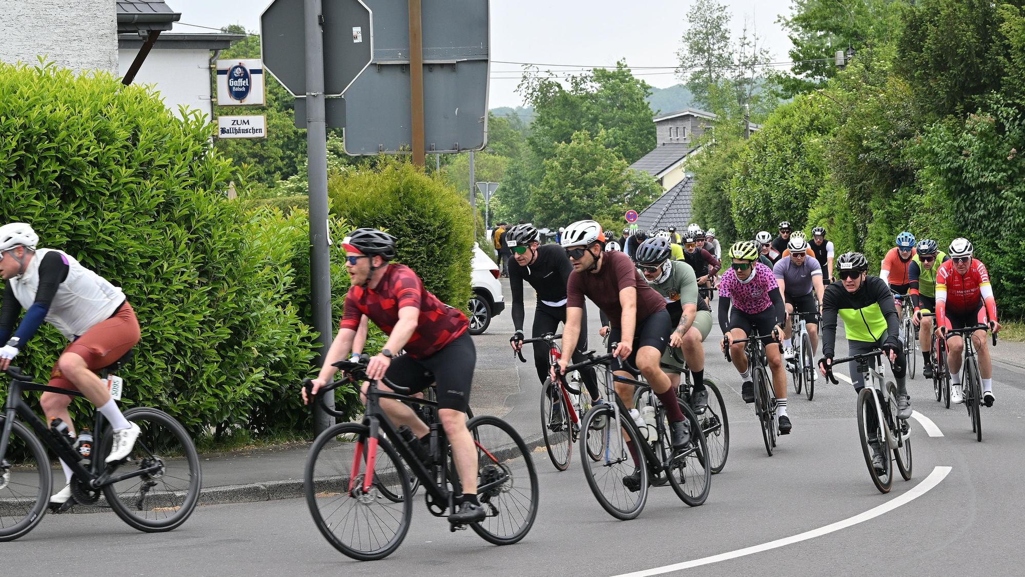 Zu sehen ist eine große Gruppe Radfahrer, die um eine Kurve biegt.