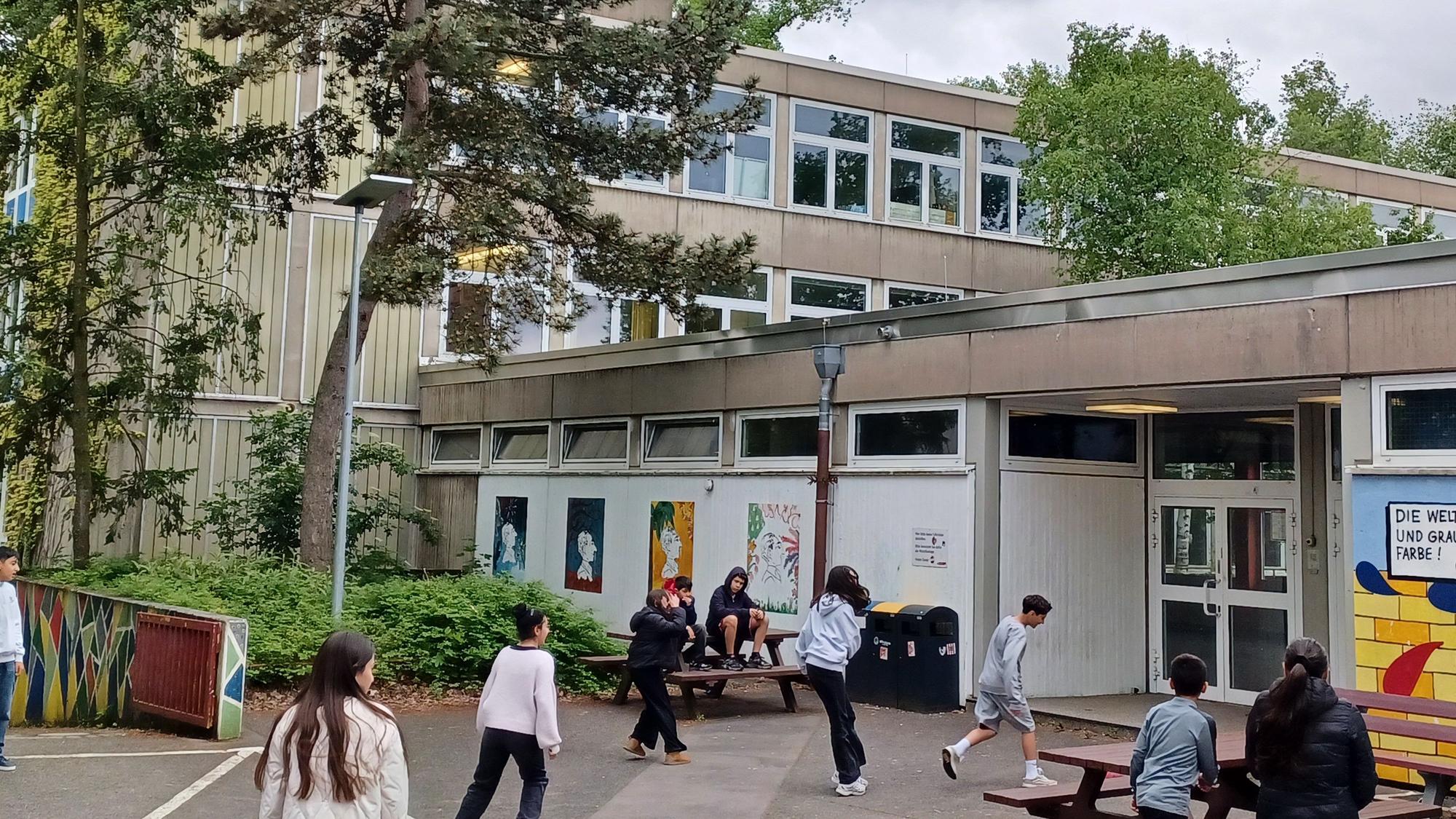 Blick auf den Eingang des Erich-Kästner-Gymnasiums, vor dem sich Schülerinnen und Schüler aufhalten.