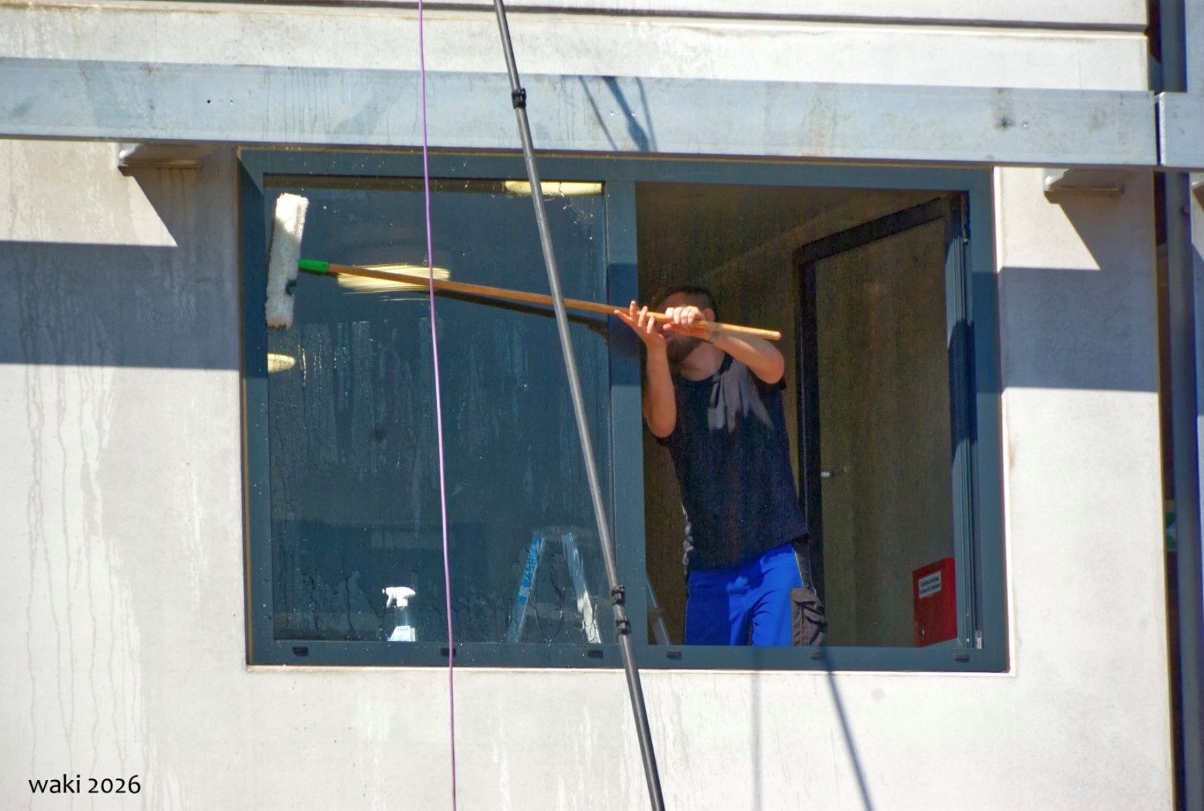 Auf dem Bild ist ein Mann zu sehen, der Fenster putzt.