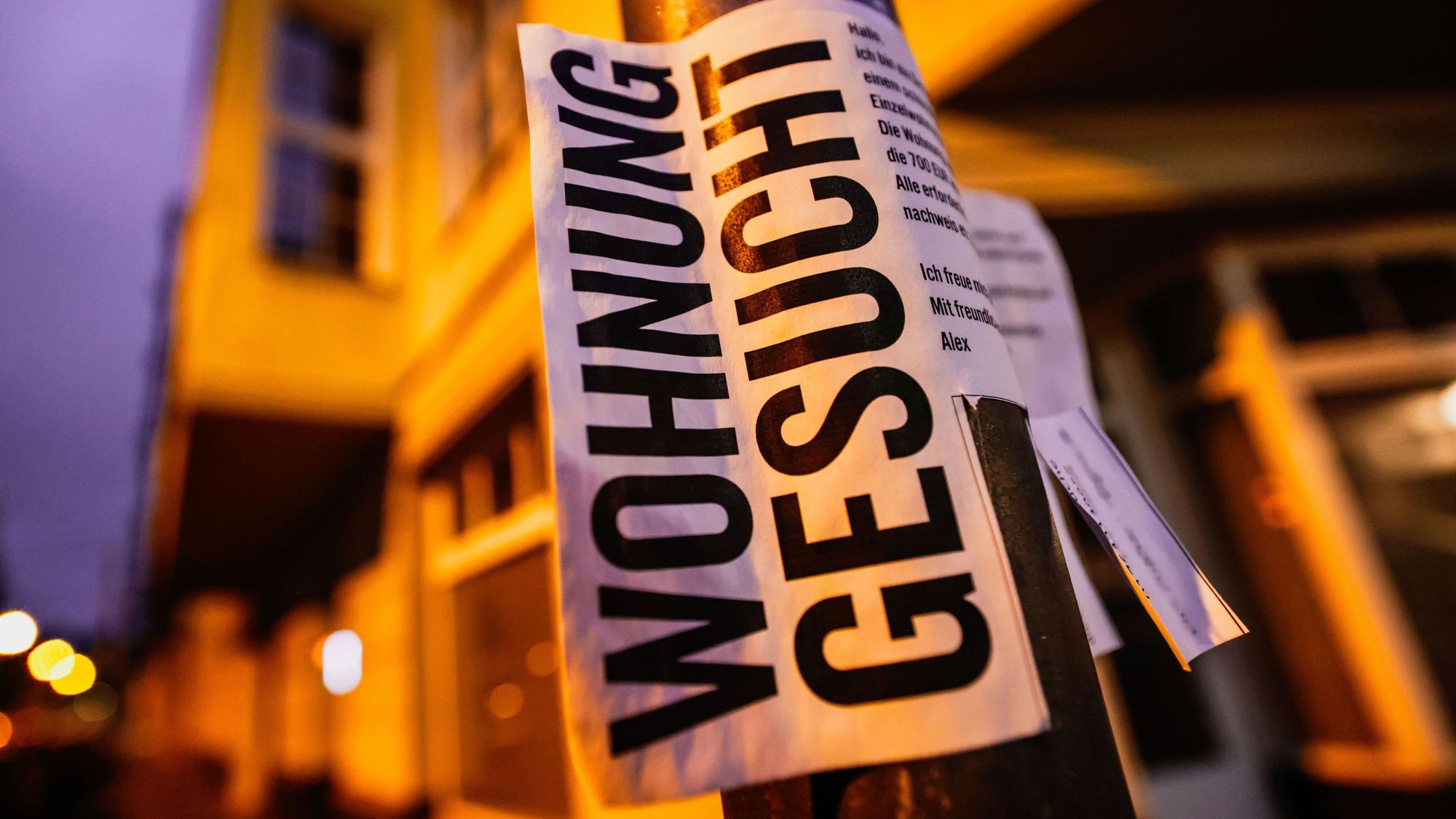 12.04.2024, Nordrhein-Westfalen, Köln: Ein Zettel mit der Aufschrift „Wohnung gesucht“ hängt vor Wohnhäusern. (zu dpa: «Frust um Wohnraum: Großstadtmieten schrecken Berufstätige ab») Foto: Oliver Berg/dpa +++ dpa-Bildfunk +++