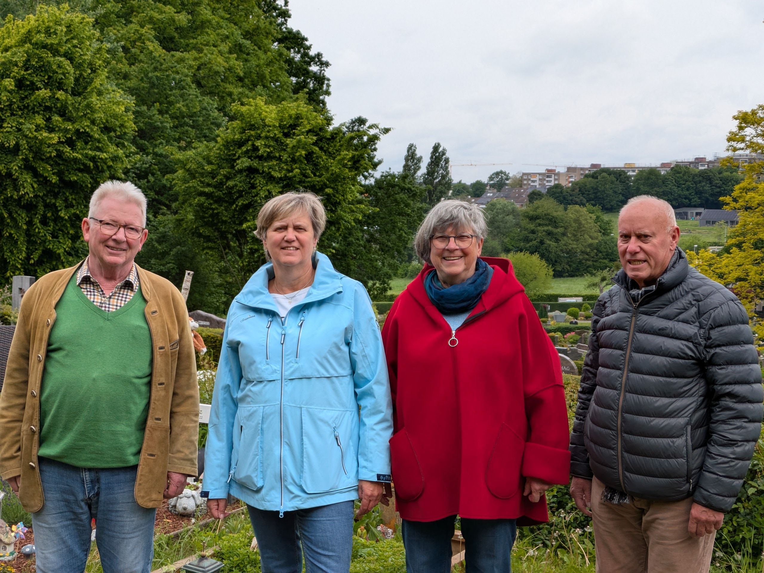 Zwei Männer und zwei Frauen stehen auf einem Friedhof.
