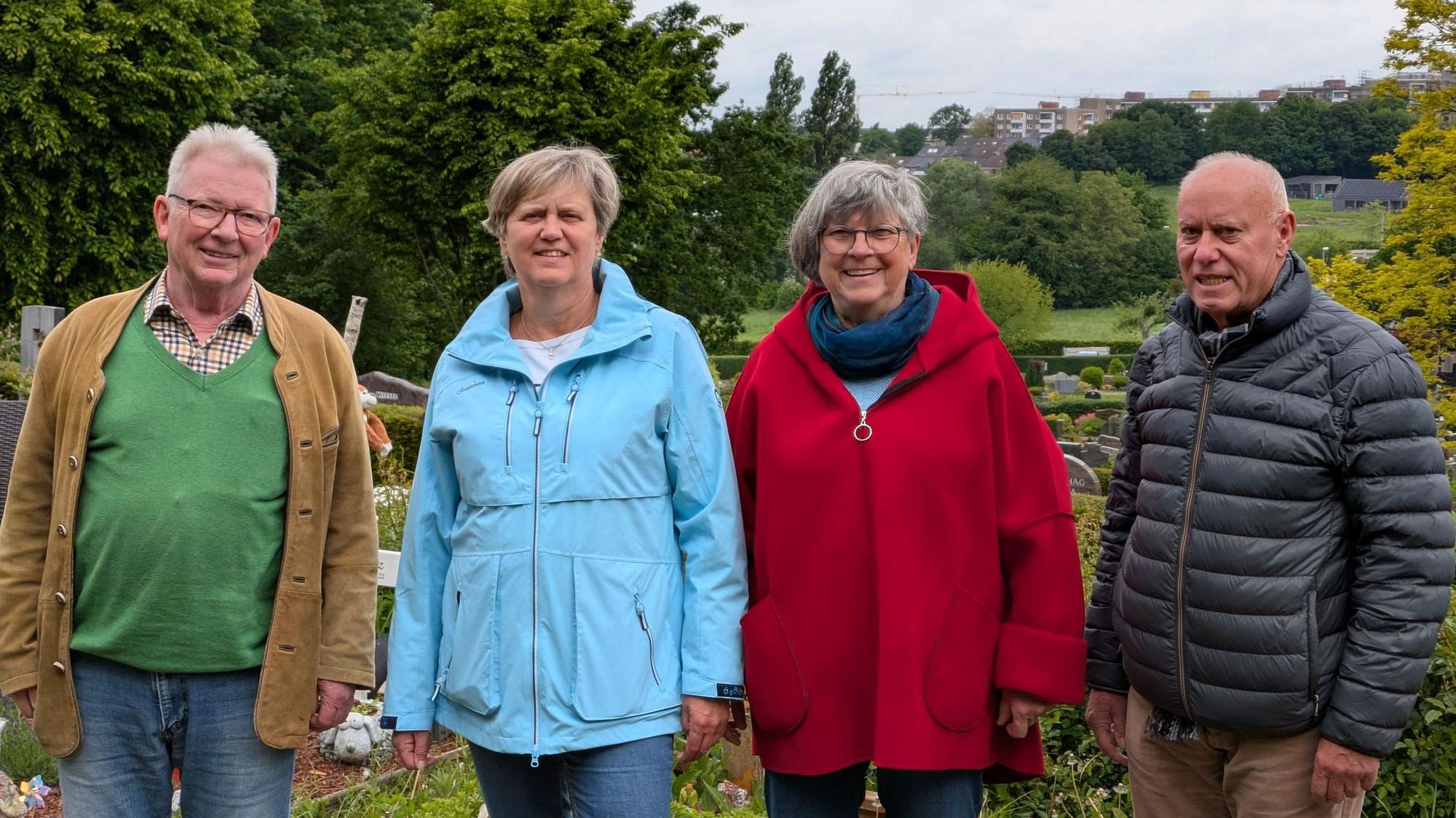Zwei Männer und zwei Frauen stehen auf einem Friedhof.