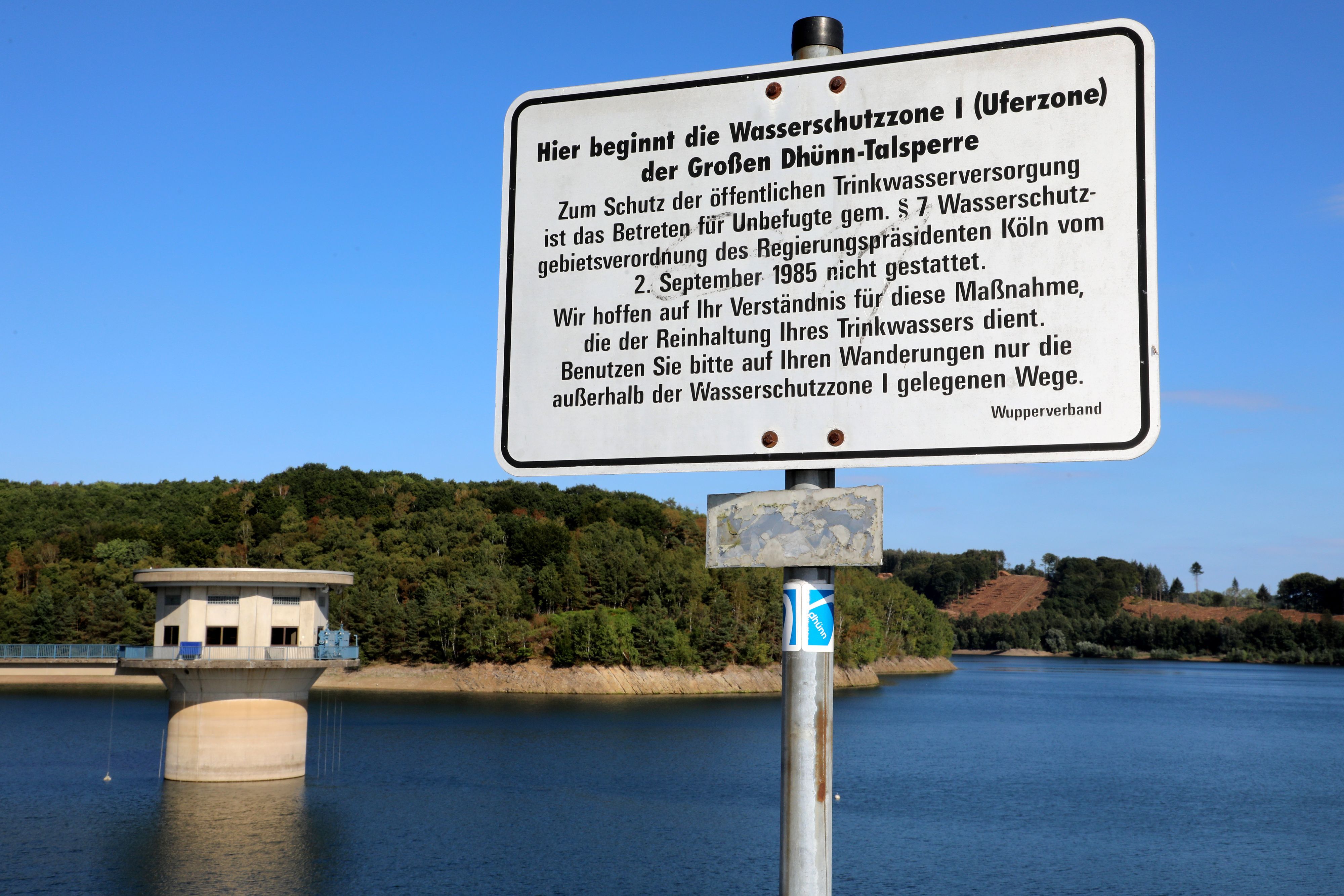 Ein Schild weis auf die Schutzzone  1 der Großen Dhünn-Talsperre hin, die im Hintergrund zu sehen ist.