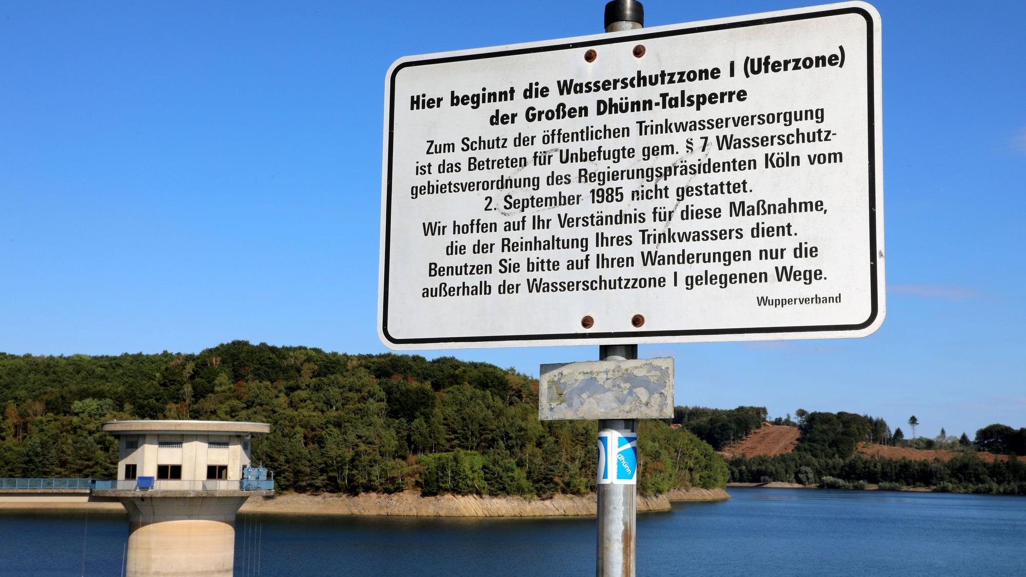 Ein Schild weis auf die Schutzzone 1 der Großen Dhünn-Talsperre hin, die im Hintergrund zu sehen ist.