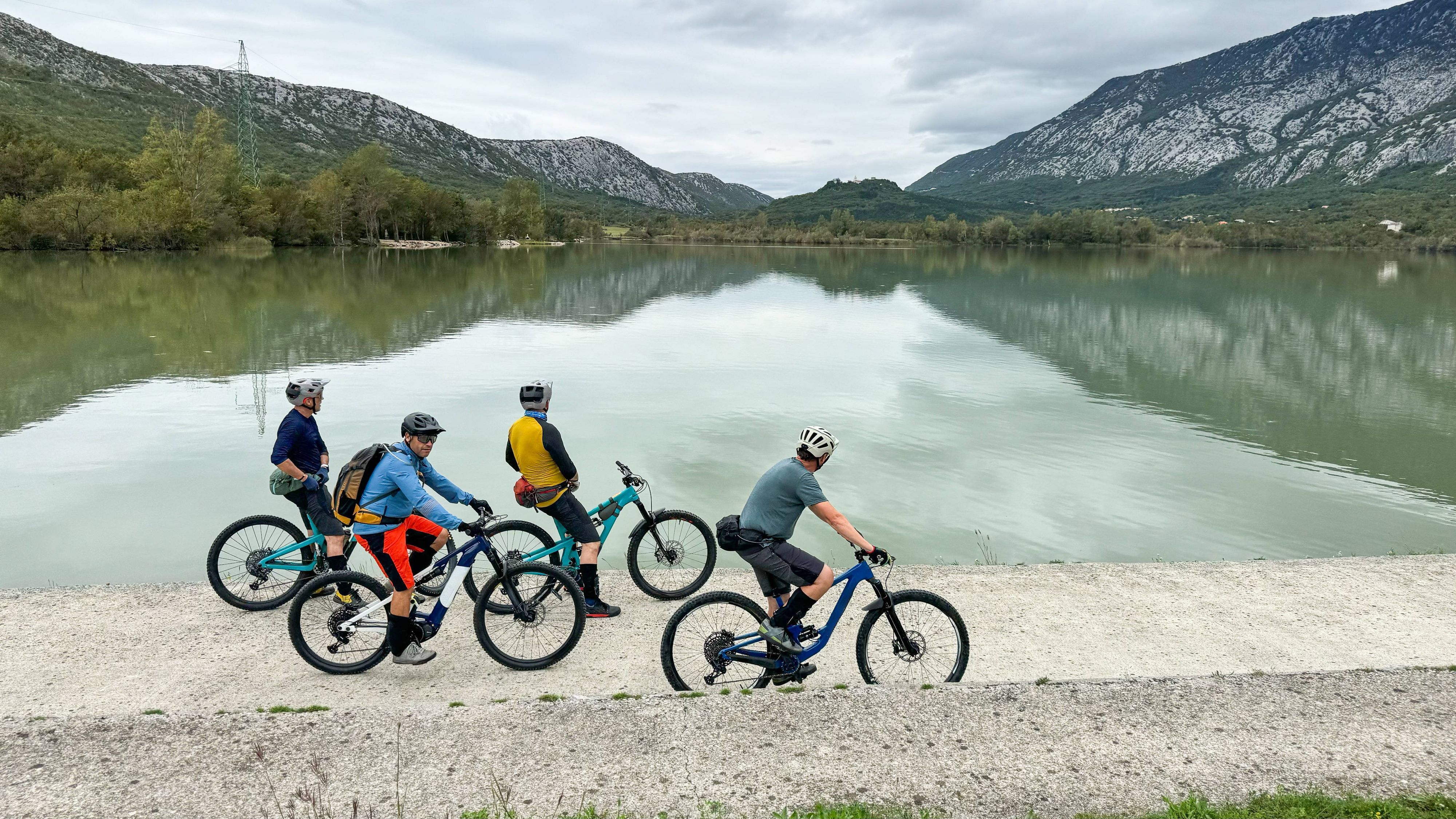 Gruppe Radfahrer mit E-Bikes am See vor Bergen