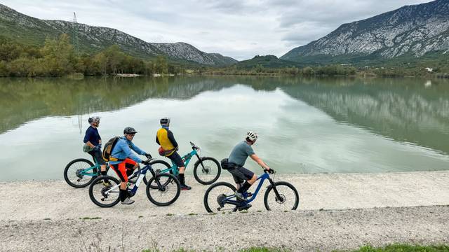 Gruppe Radfahrer mit E-Bikes am See vor Bergen
