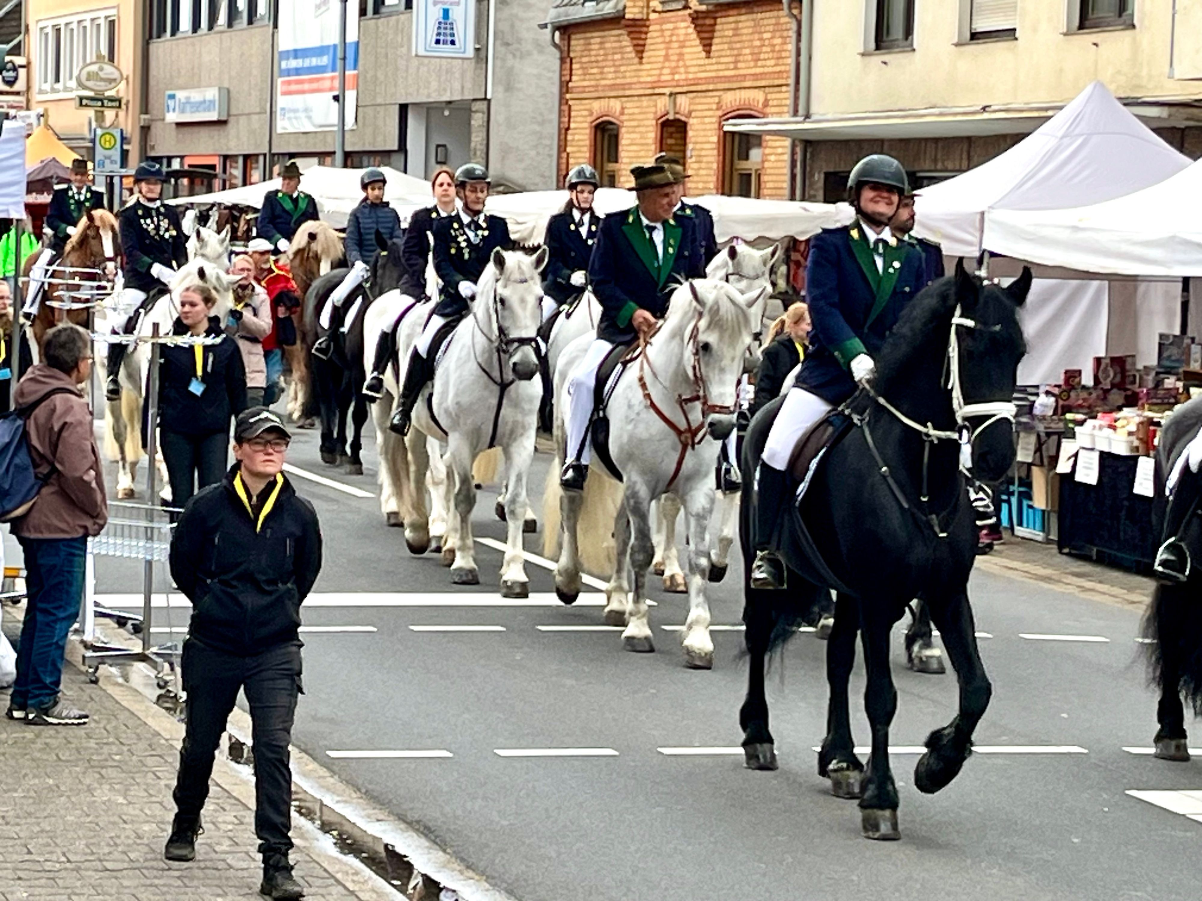 Auf einer Straße sind Reiter und Pilger zu Fuß zu sehen.