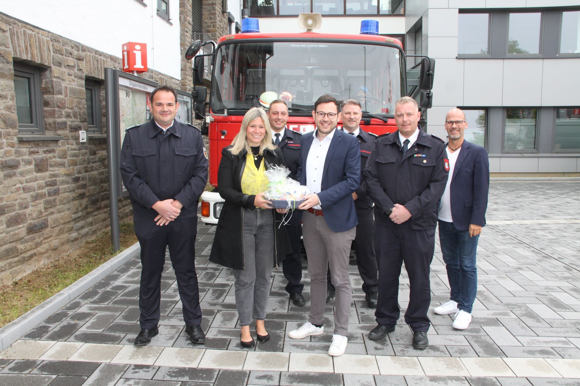 Die Obengenannten stehen vor einem Feuerwehrauto, Jennifer Meuren und Emmanuel Kunz halten ein Geschenk.