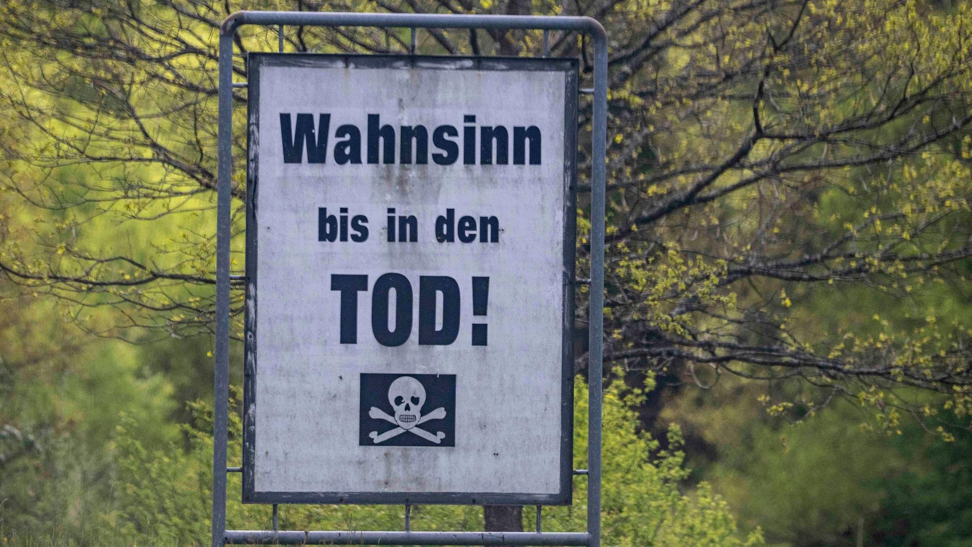 Das Bild zeigt eine Warntafel an einer Straße in der Eifel. „Wahnsinn bis in den Tod“ ist darauf zu lesen.
