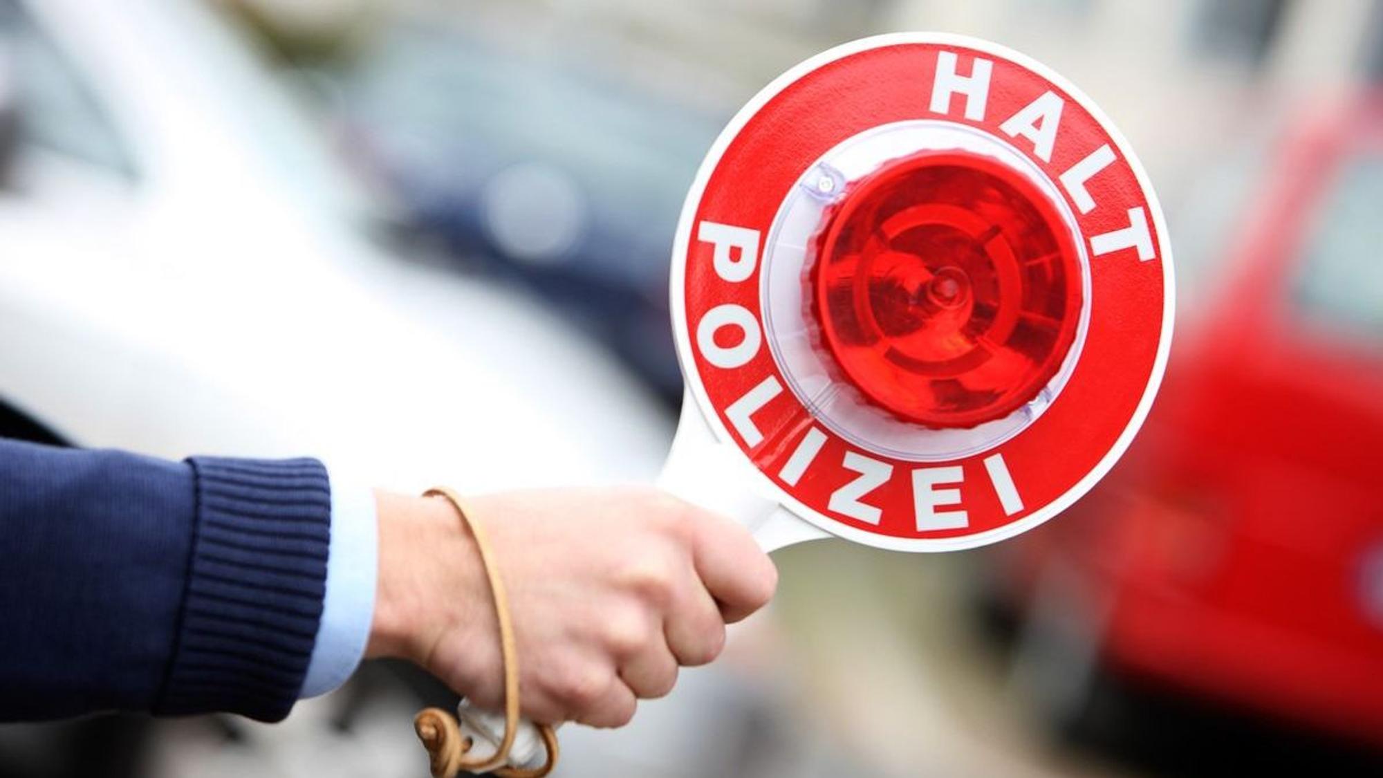 Eine Polizeikelle liegt auf dem Armaturenbrett eines Polizeiautos. (Symbolbild)