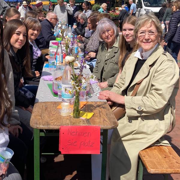 Zu sehen sind Schülerinnen an einem Tisch mit Vertretern einer älteren Generation