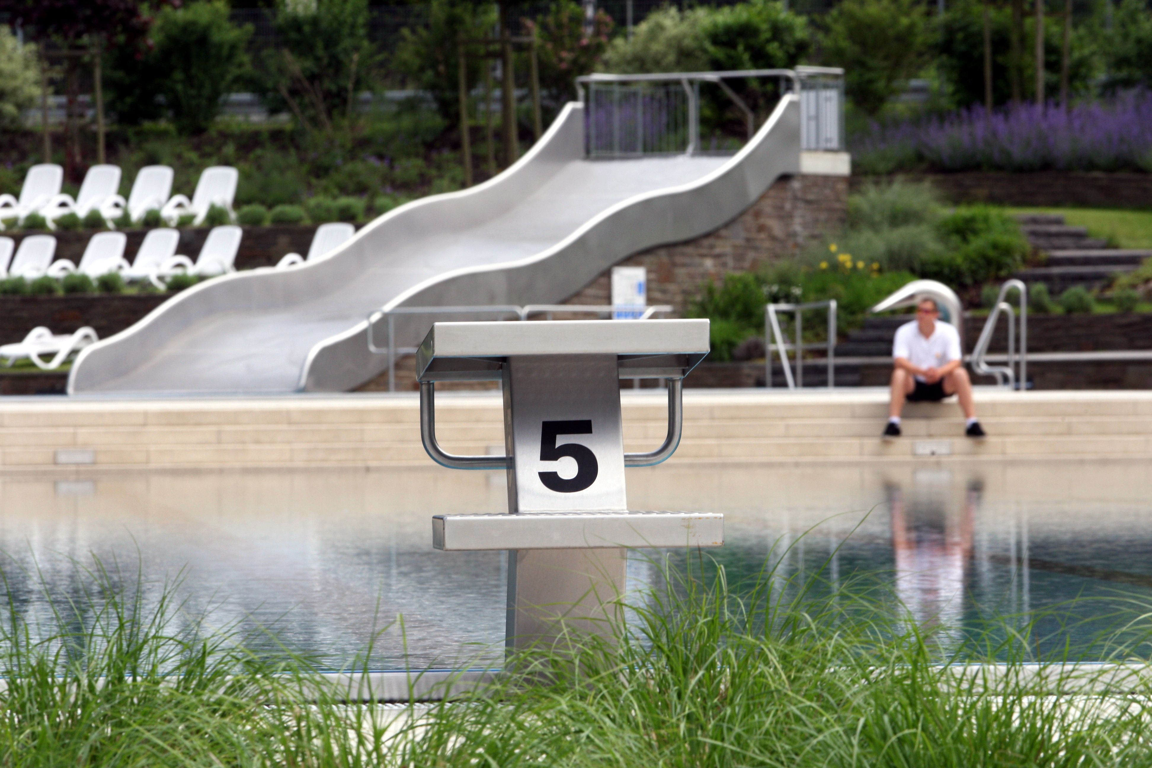 Ein Schwimmmeister sitzt am Rand des noch leeren Nichtschwimmerbeckens in Rösrath-Hoffnungsthal.
