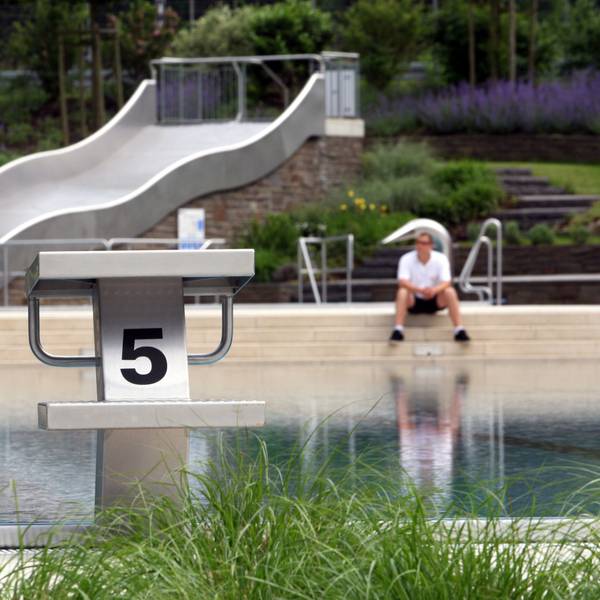 Ein Schwimmmeister sitzt am Rand des noch leeren Nichtschwimmerbeckens in Rösrath-Hoffnungsthal.