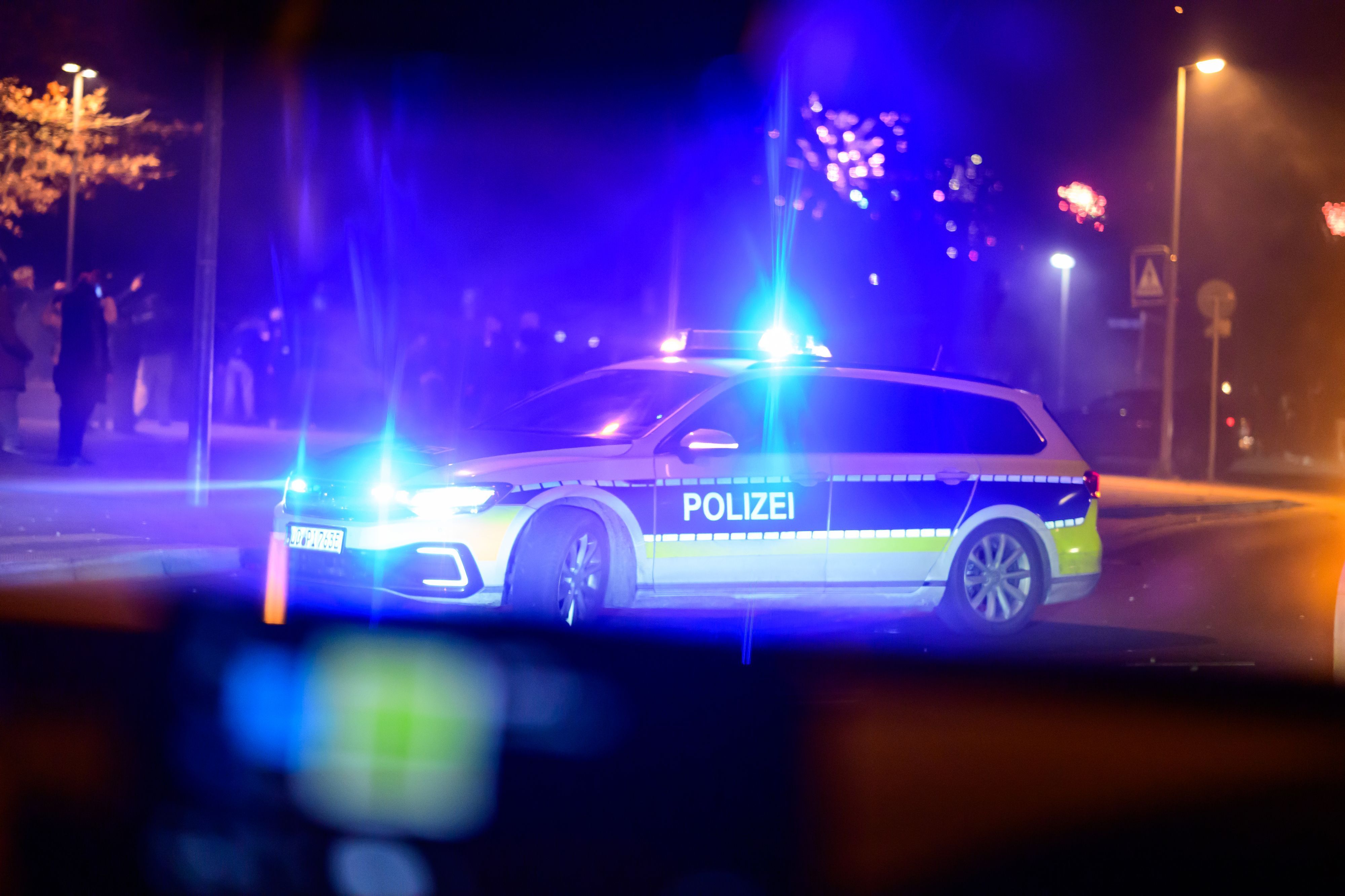 Ein Einsatzfahrzeug der Polizei steht nachts mit Blaulicht auf einer Straße.