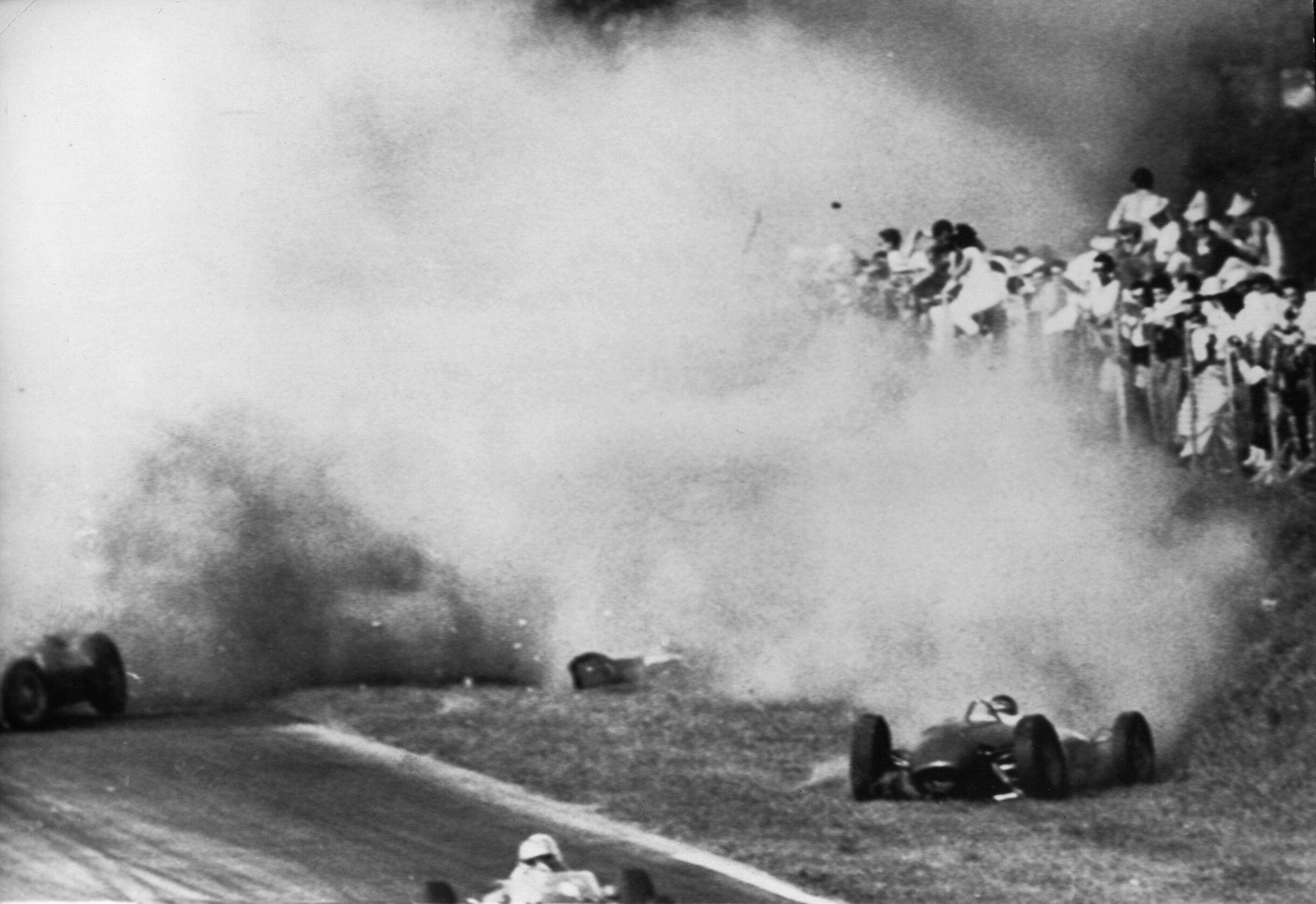 Dichter Qualm liegt nach der Kollisions-Tragödie vom 10.09.1961 über der Unglückstätte von Monza. Links der Ferrari des deutschen Formel-1-Fahrers Wolfgang Graf Berghe von Trips, der kurz nach dem Start zum Großen Preis von Italien bei der Doppelkollision erst mit dem Engländer Jim Clark und dann mit dessen Landsmann Ashmore den Tod findet. Rechts der Wagen Clarks, durch den 15 Zuschauer in den Tod gerissen werden.