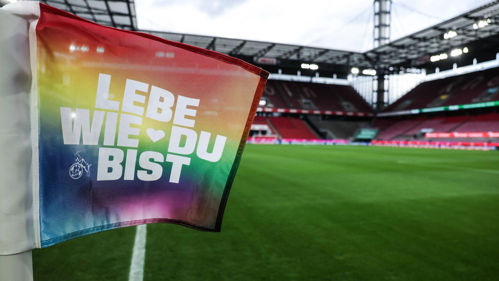 Eine Eckfahne in Regenbogenfarben mit der Aufschrift „Lebe wie du bist“ und dem Logo des 1. FC Köln steht im Rheinenergie-Stadion. (Archivbild)