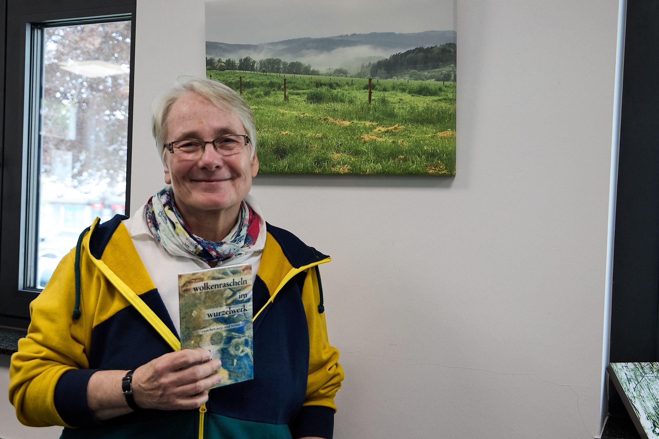 Eine Frau hält ein dünnes Buch in der Hand, das sie geschrieben hat.
