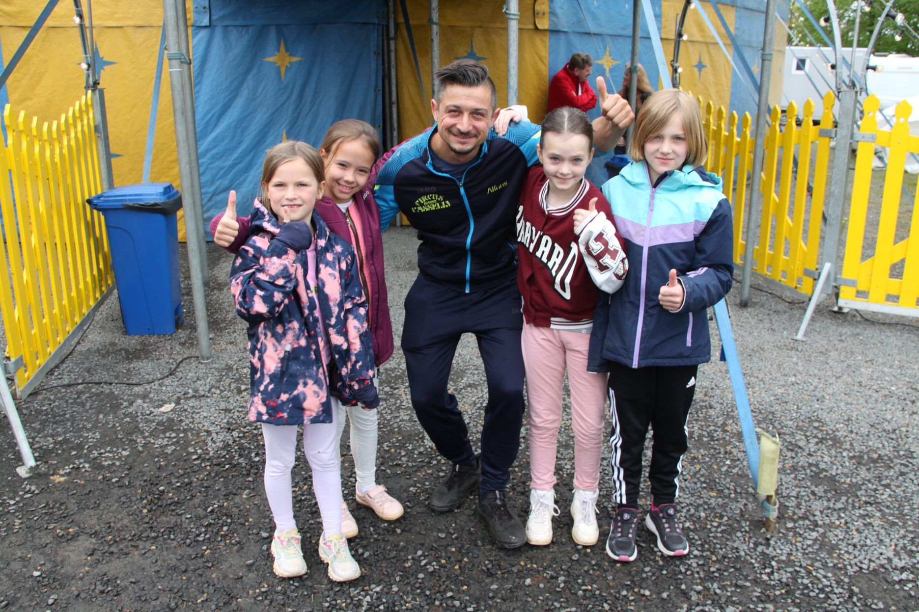 Vier Mädchen der Grundschule Dahlem und ihr Trainer Alfons Casselly stehen vor einem Zirkuszelt.