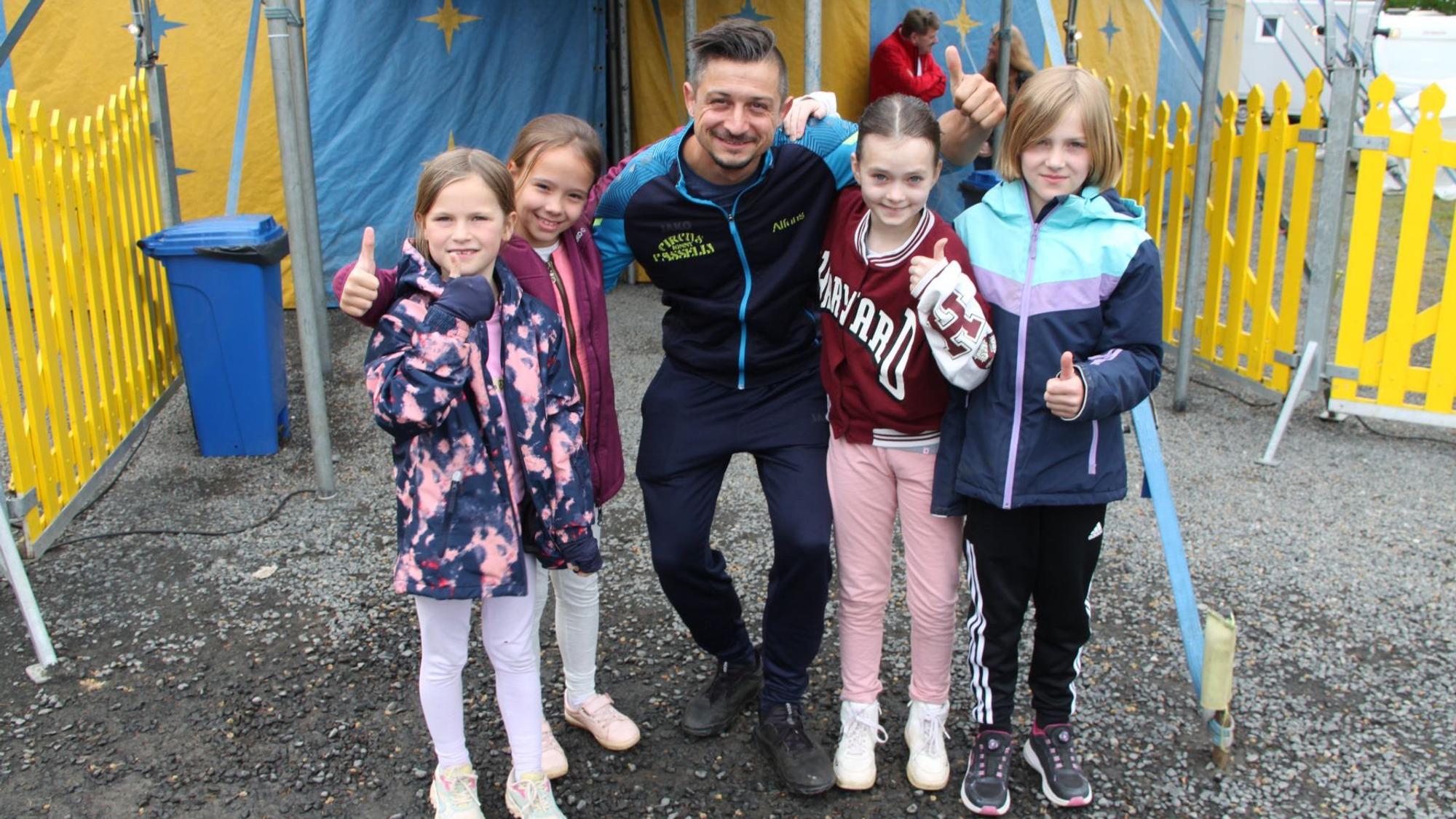 Vier Mädchen der Grundschule Dahlem und ihr Trainer Alfons Casselly stehen vor einem Zirkuszelt.