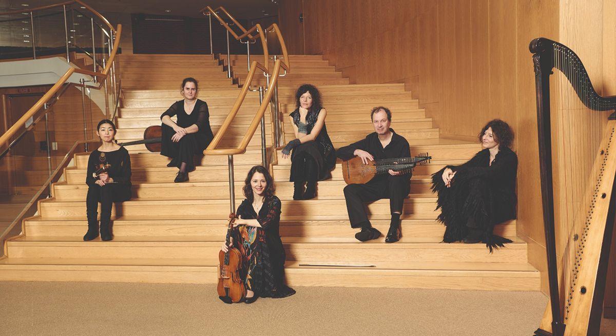 Musikerinnen und Musiker sitzen neben- und voreinander auf einer Treppe.