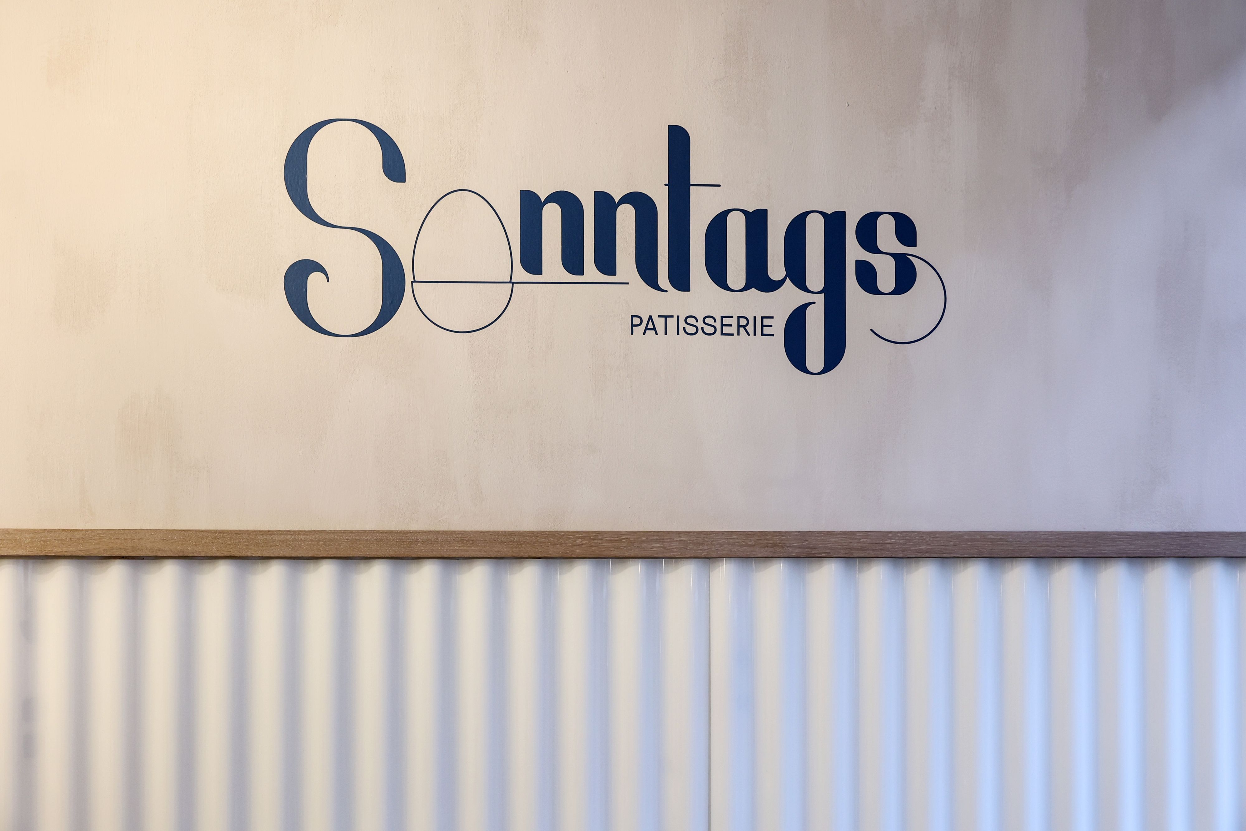 Logo von der Sonntags Patisserie auf der Wand im Café.