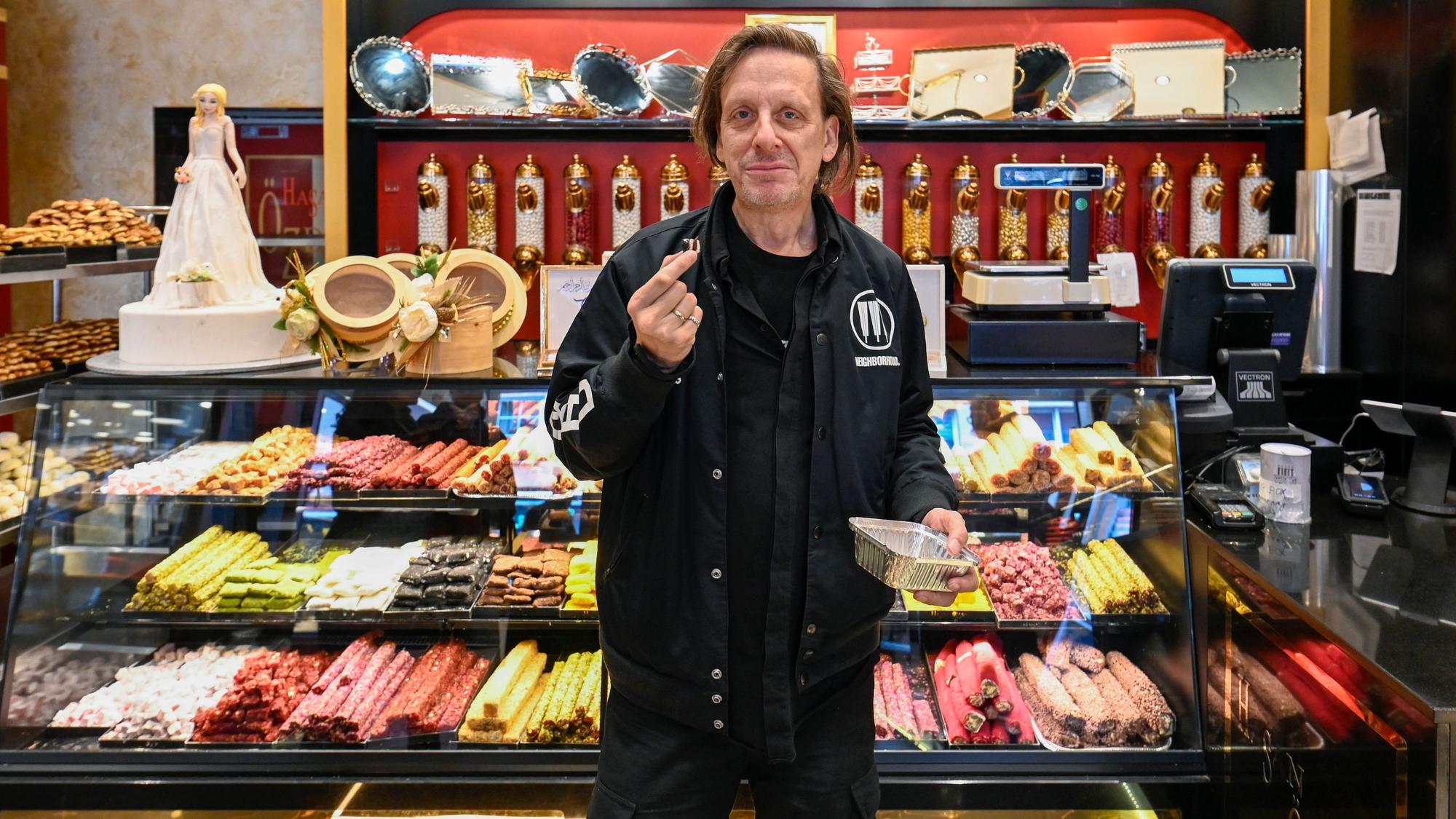 Ein Mann in Schwarz steht vor einer Süßwaren-Theke voller bunter Zuckerwaren.