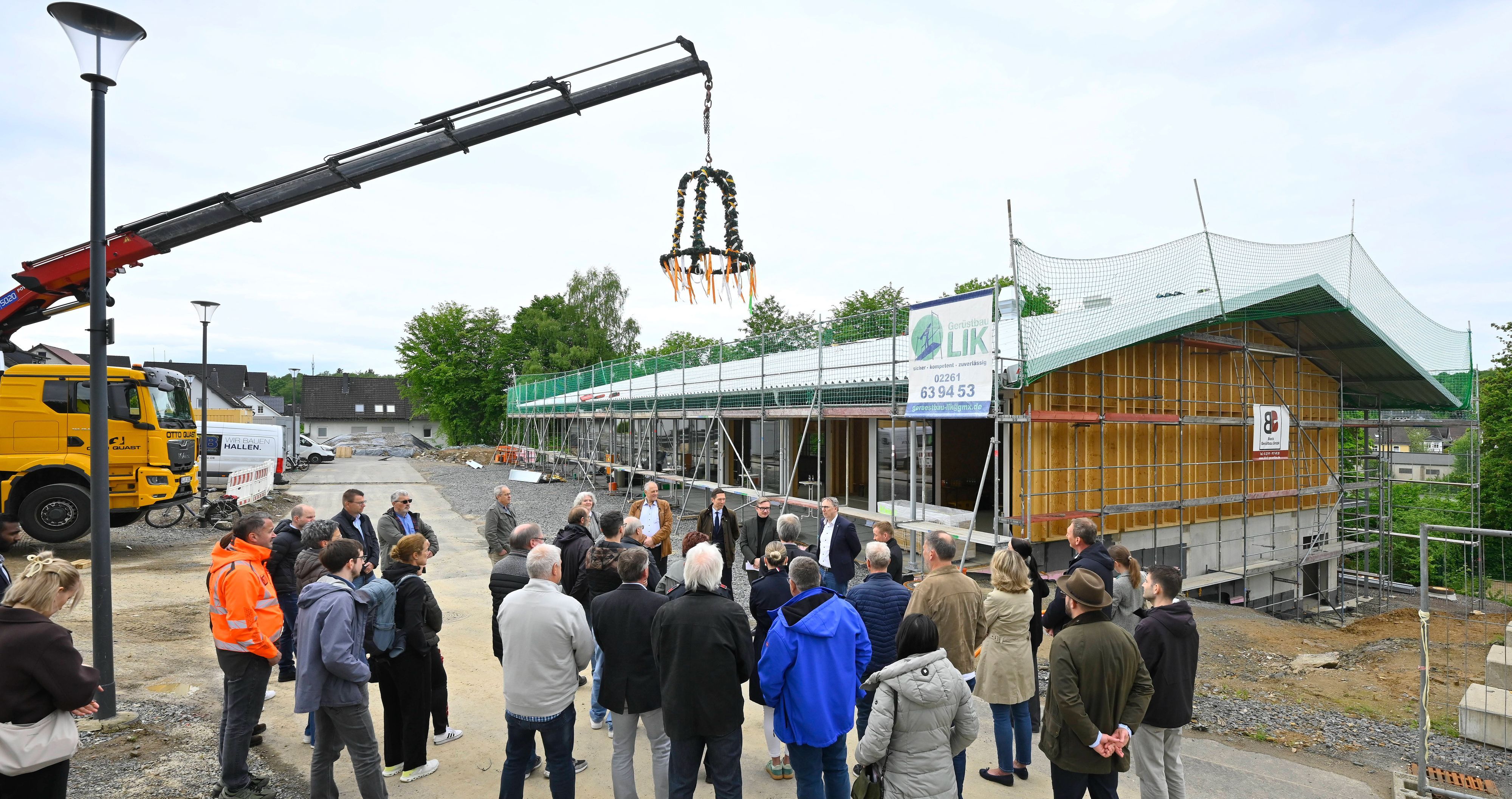 Zu sehen ist die neue Sporthalle, über der ein Richtkranz schwebt.