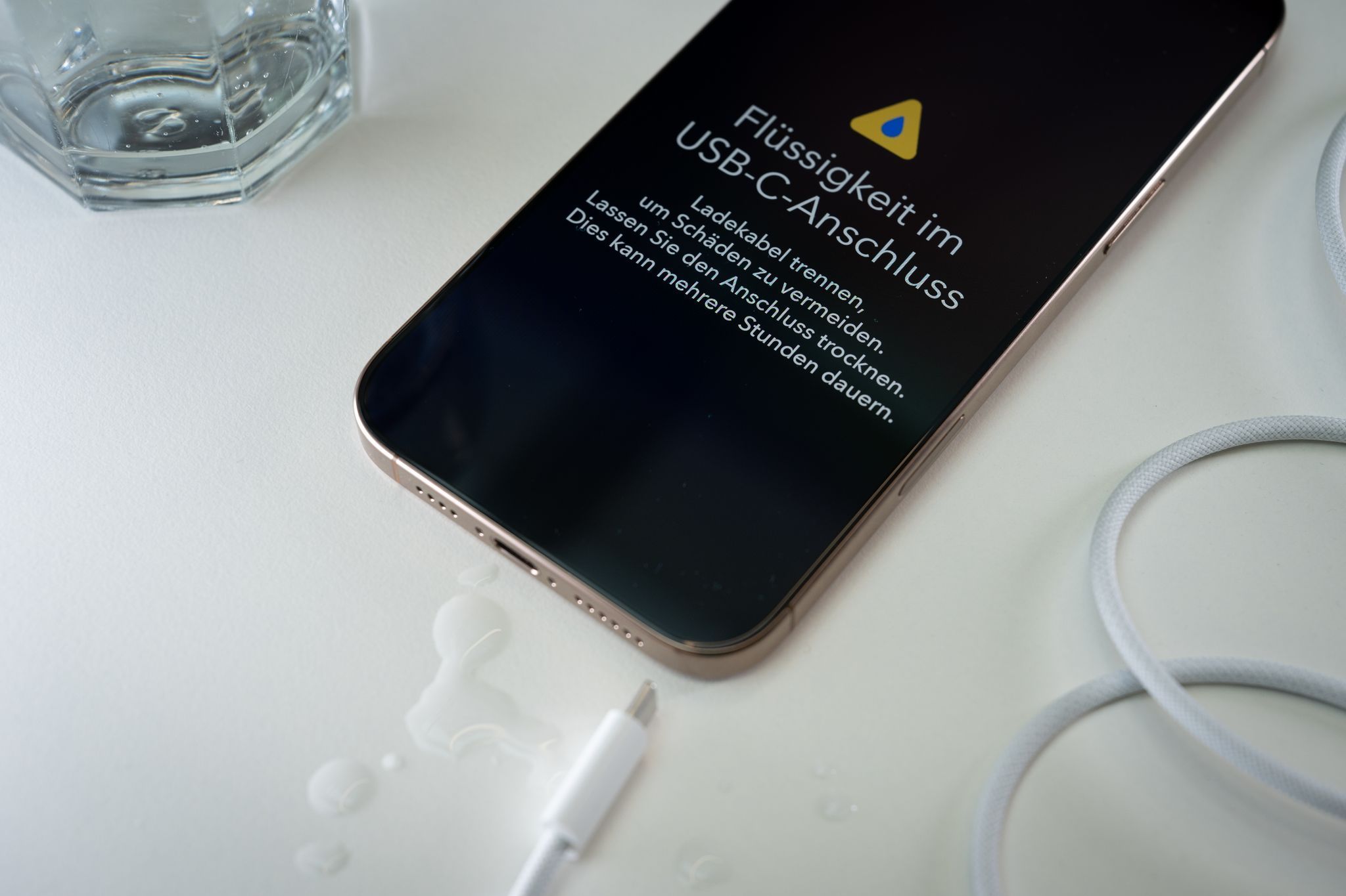 Ein iPhone mit einer Flüssigkeitswarnung und Wassertropfen
