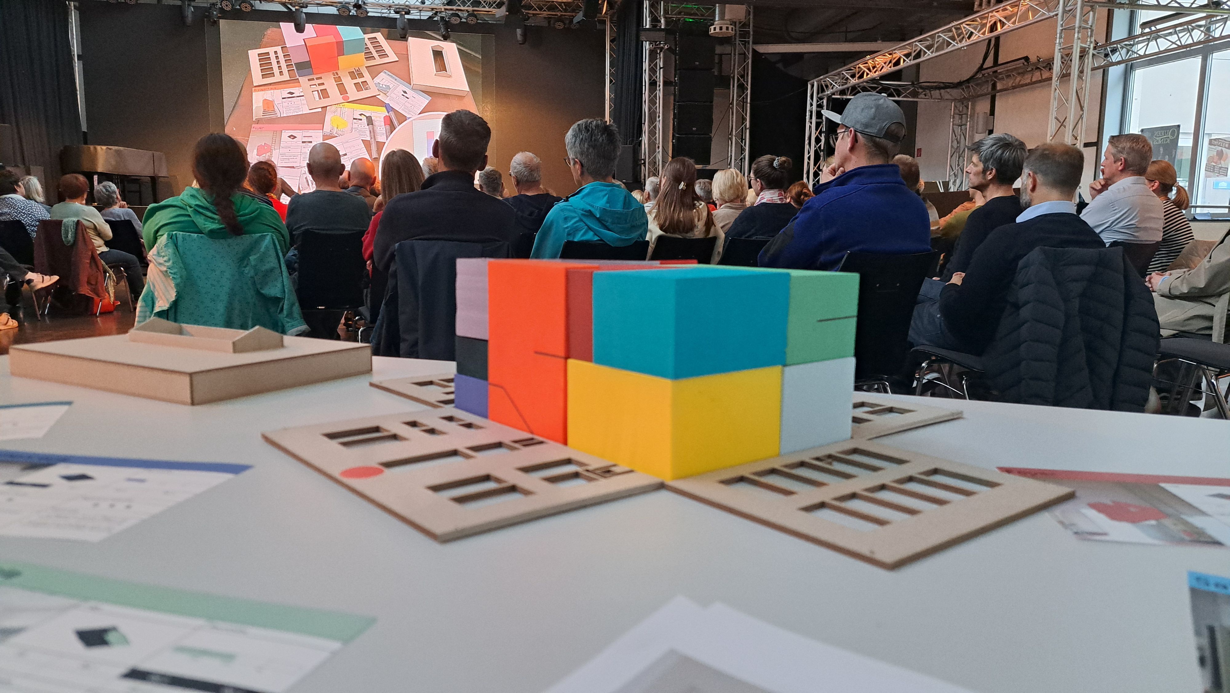Das Foto zeigt viele Besucher der Inforveranstaltung und ein Modell des Radium-Turbinenhauses im Vordergrund.