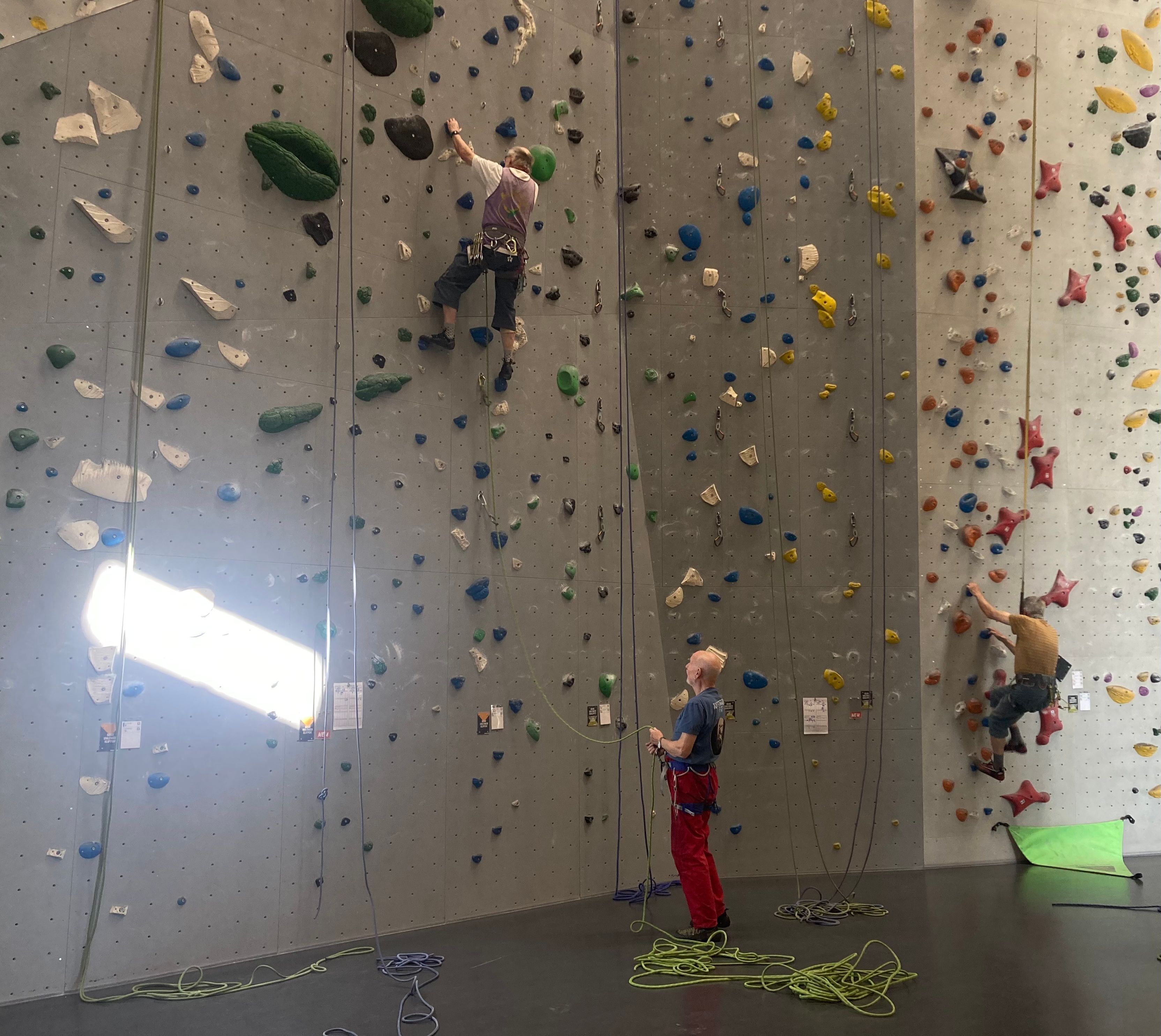 Auf dem Bild sind drei Männer an einer Kletterwand zu sehen.
