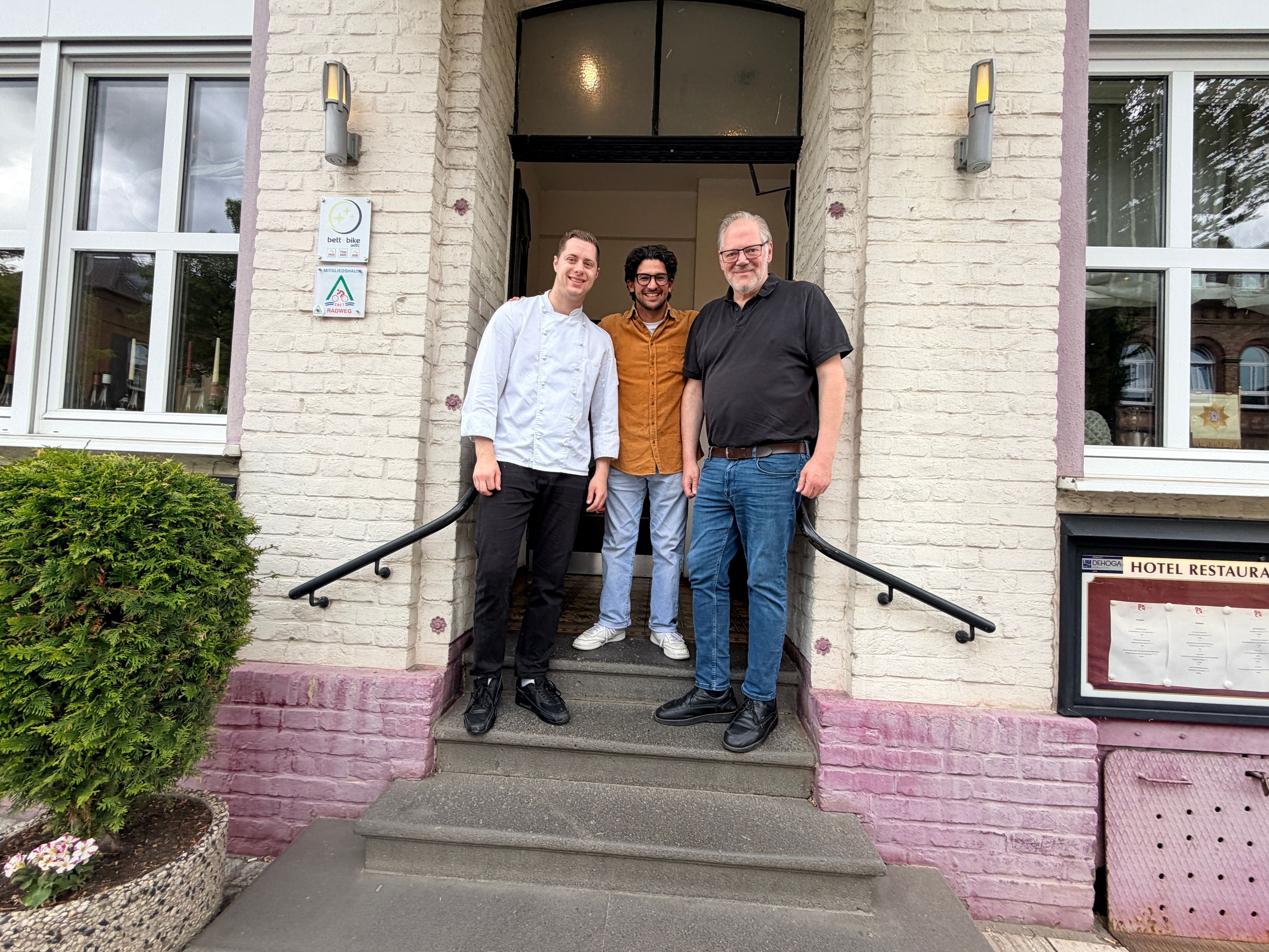 Die drei Männer stehen auf der Eingangstreppe zum Hotel Restaurant Rothkopf.