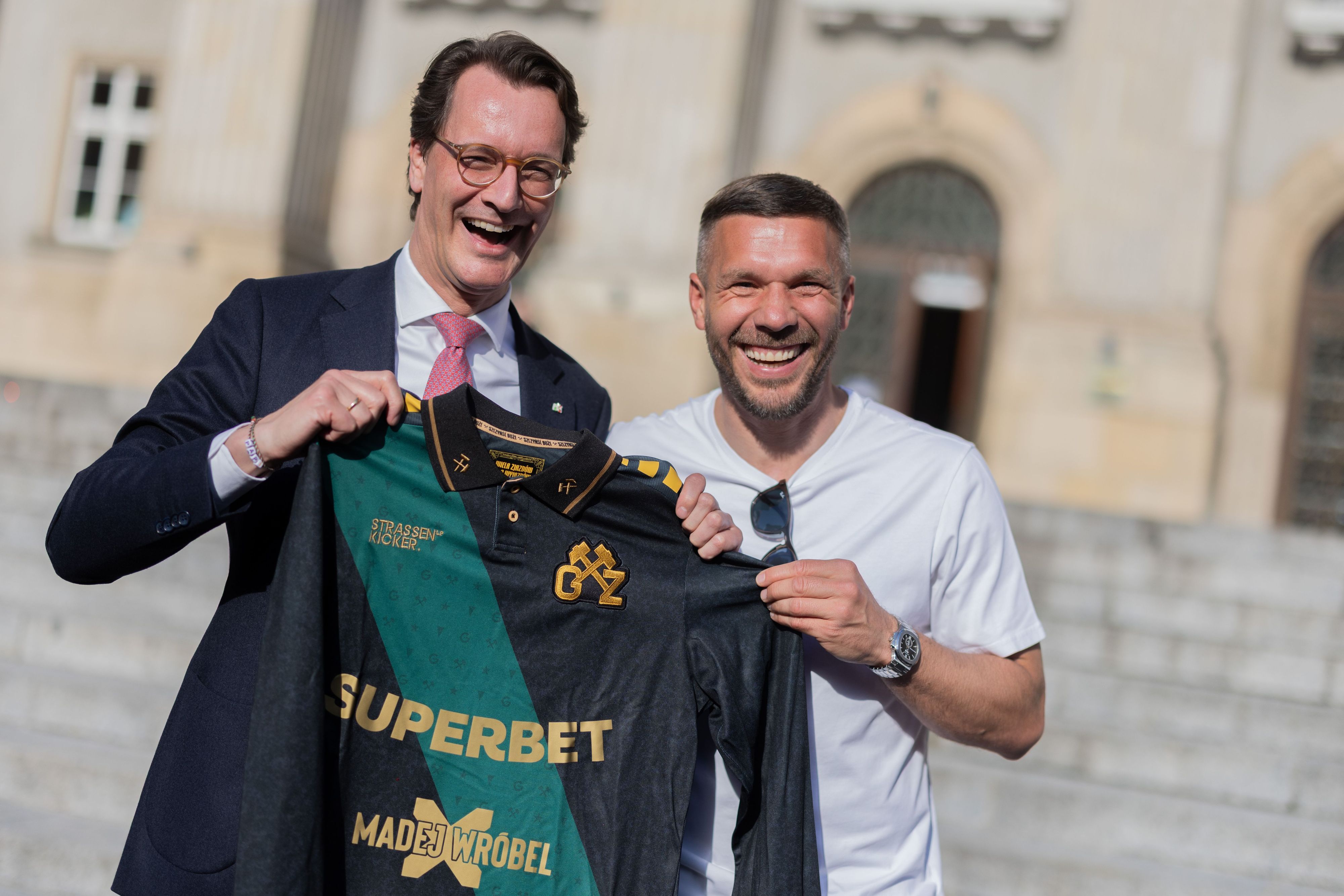 Lukas Podolski (r.), ehemaliger Fußball-Nationalspieler und Spieler beim polnischen Erstligisten Górnik Zabrze, überreicht Hendrik Wüst (CDU), Ministerpräsident von Nordrhein-Westfalen, ein Trikot.