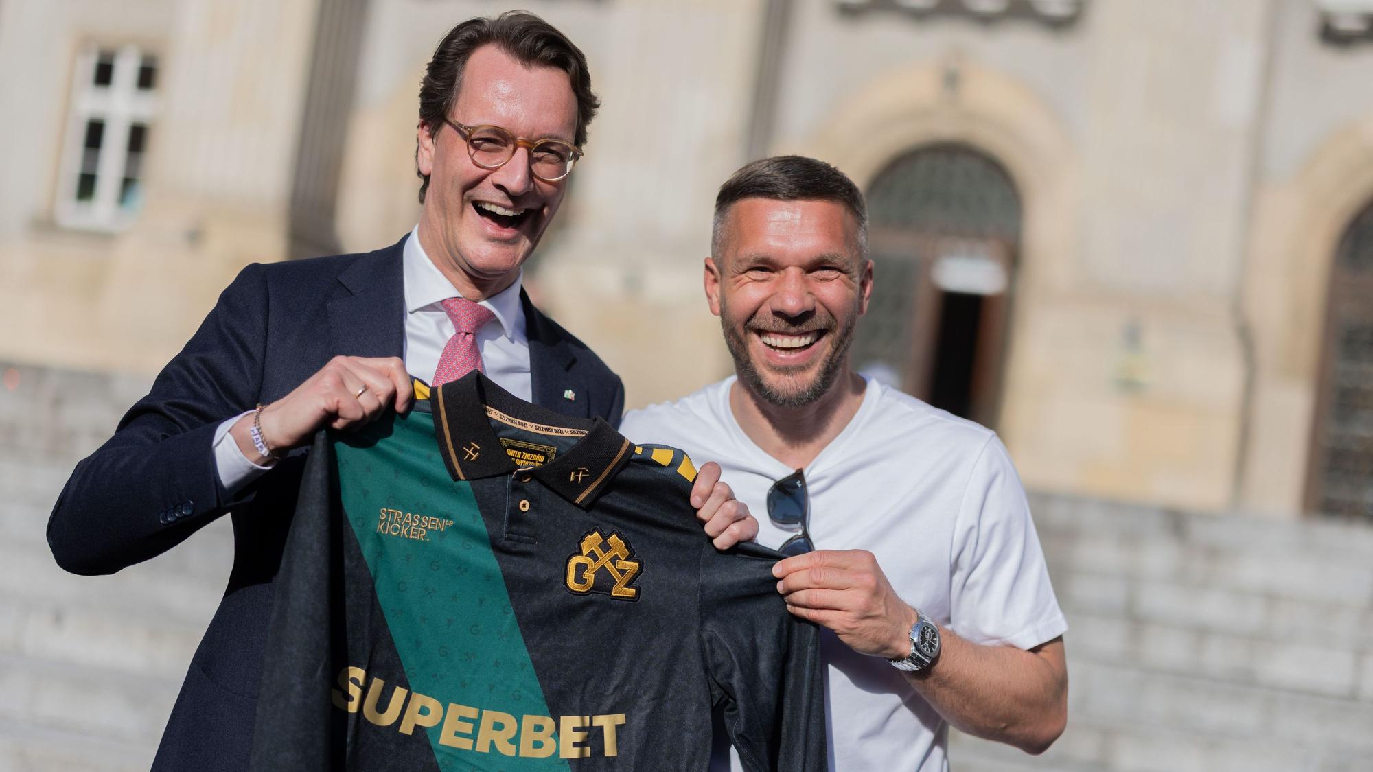 Lukas Podolski (r.), ehemaliger Fußball-Nationalspieler und Spieler beim polnischen Erstligisten Górnik Zabrze, überreicht Hendrik Wüst (CDU), Ministerpräsident von Nordrhein-Westfalen, ein Trikot.