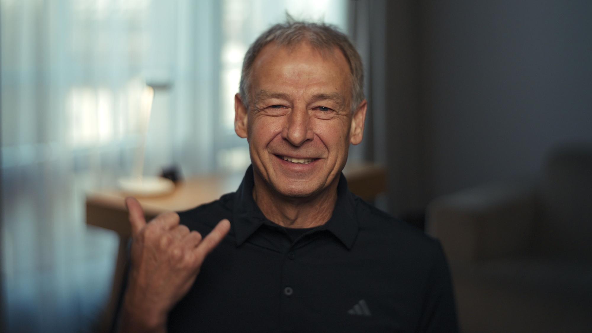 Ein Mann lächelt in die Kamera und zeigt das Rock ‚n‘ Roll-Handzeichen.