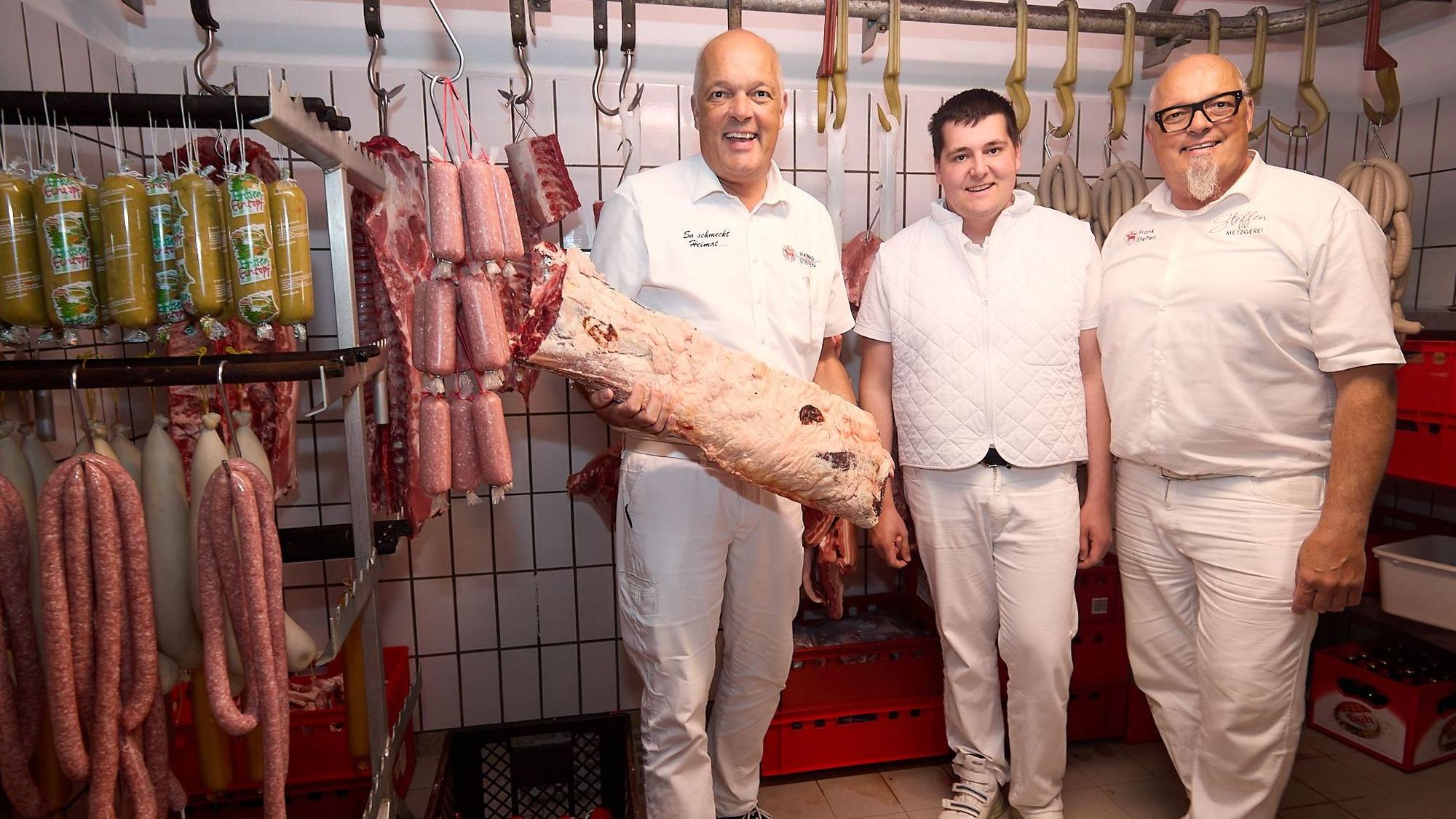 Drei Männer in weißer Kleidung stehen in den Produktionsräumen der Metzgerei Steffen in Gemünd.